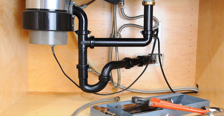 A sink with a garbage disposal and a wrench underneath it.