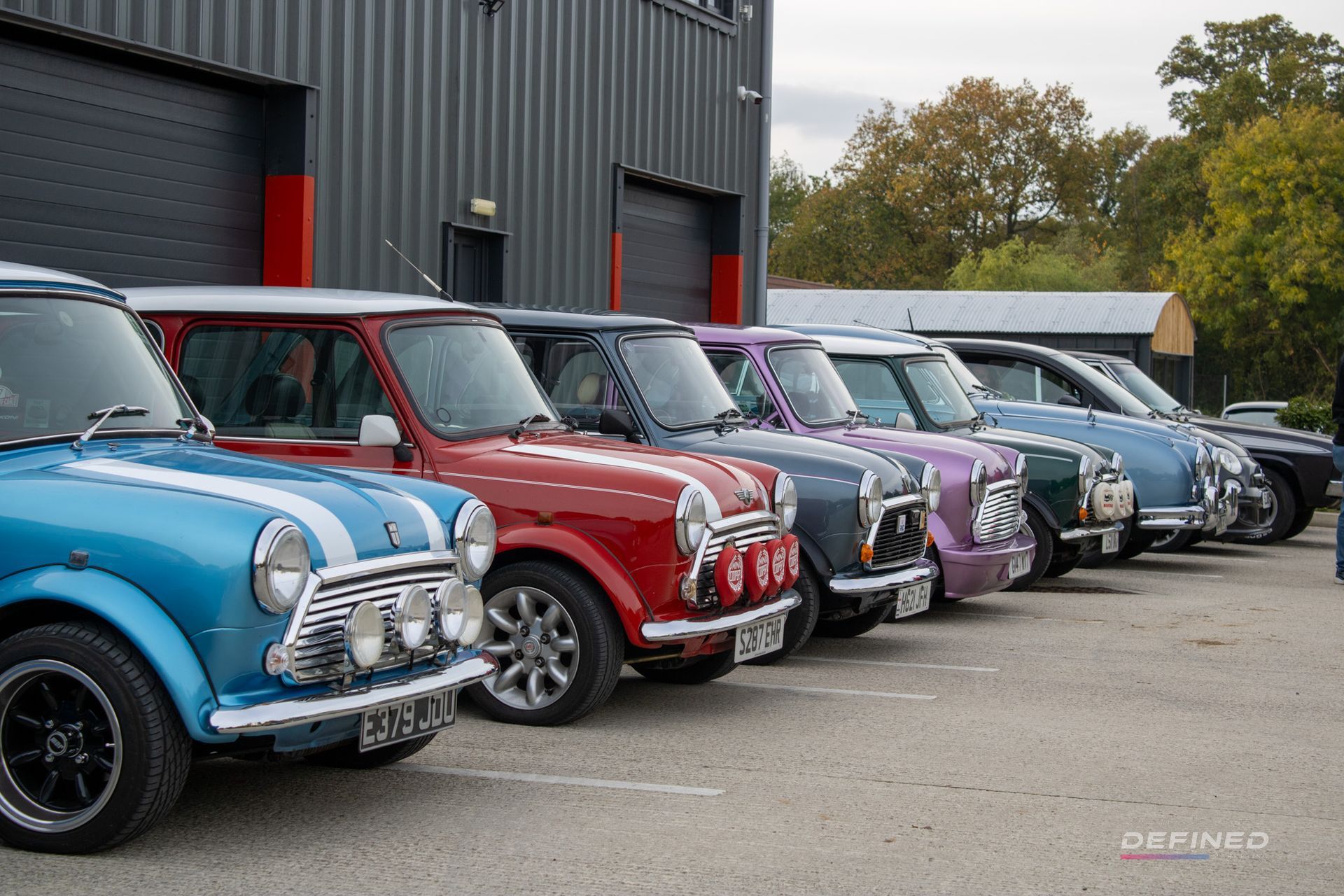 Row of colorful classic Mini Coopers parked outside a building.