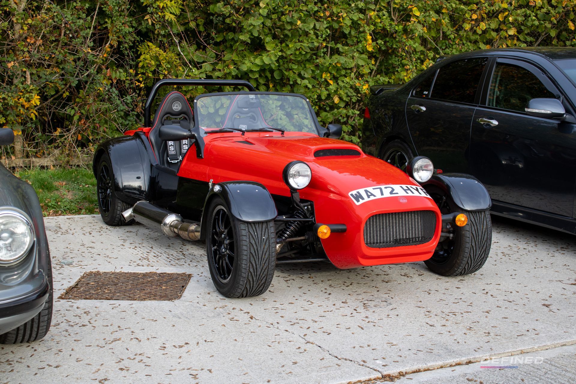 Red and black sports car parked on concrete, front view.
