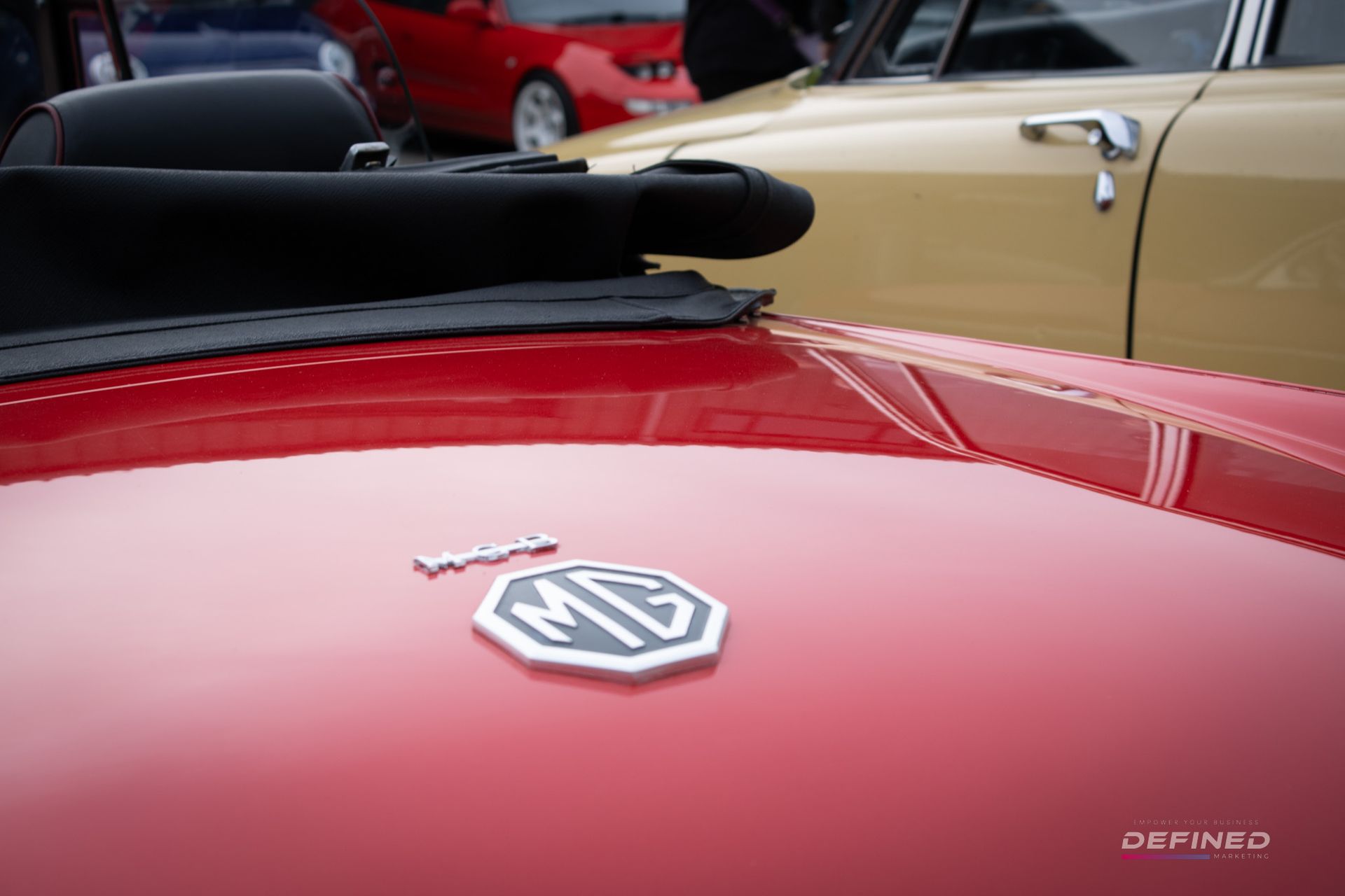 Red MG convertible car hood with MG emblem. Other cars in background.