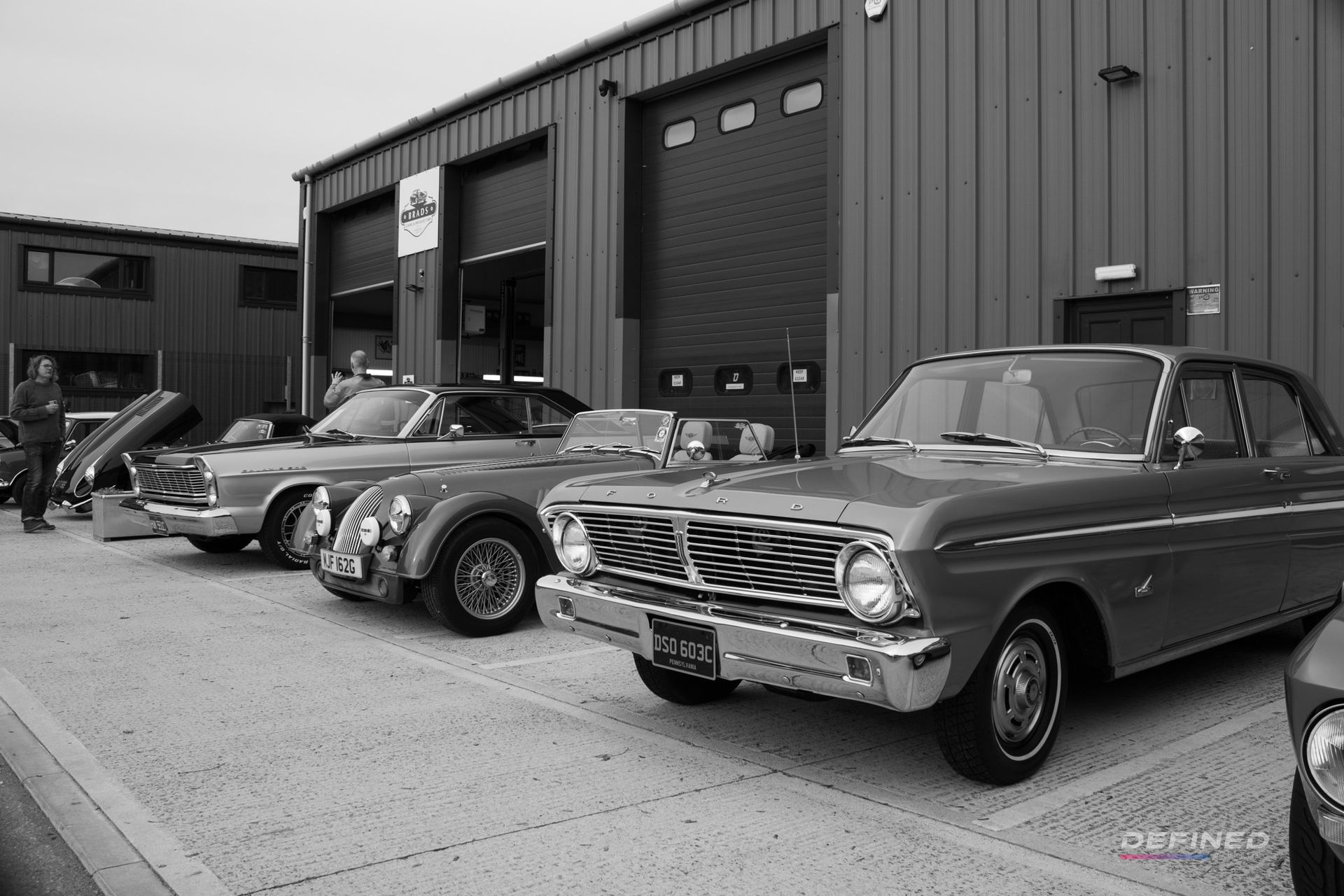 Classic cars parked in front of a building with garage doors.