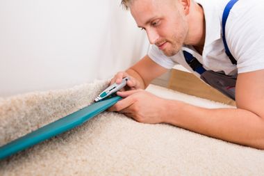 Floor Installation — Man Cutting Carpet With Cutter in Hamburg, NY