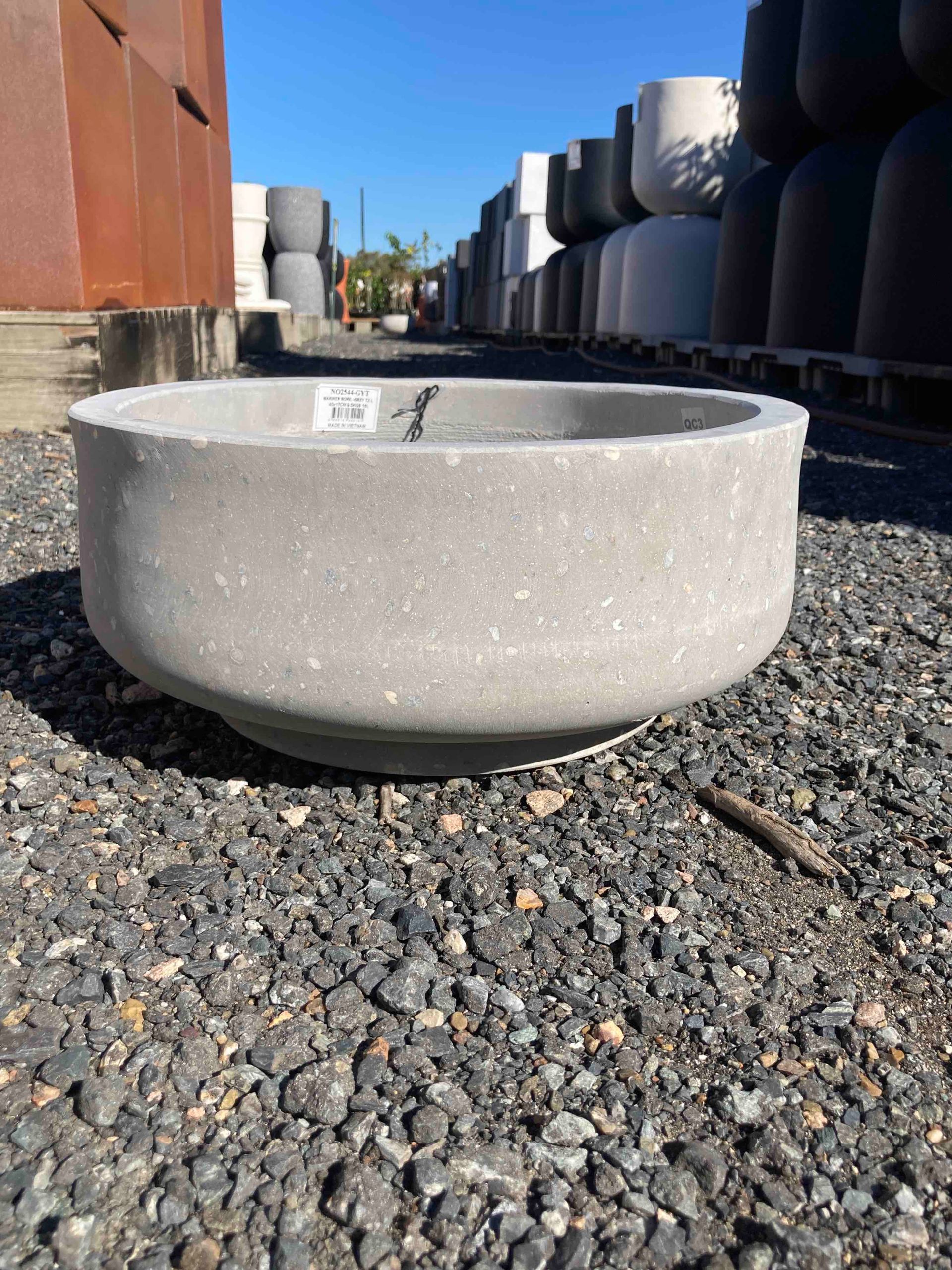 Concrete round basin on gravel in an industrial yard with large metal tanks in the background