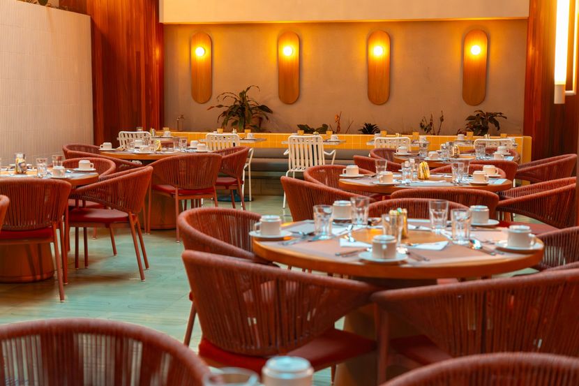 Salón comedor con mesas café, sillas y luz cálida en hotel en San Andrés con restaurante.