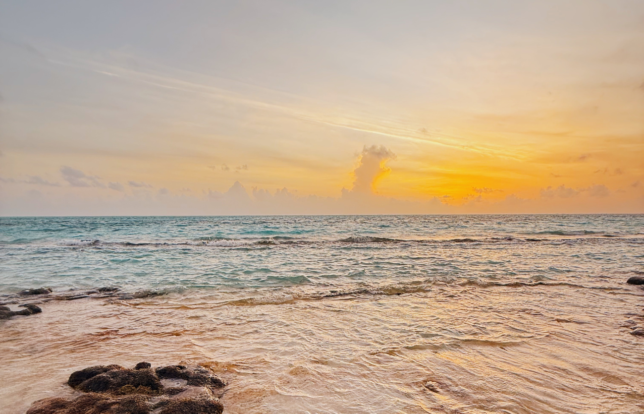 Playa de San Andrés al atardecer con embarcación en la orilla, viajar a San Andrés sin afán y descansar en Zapadilly Tree.