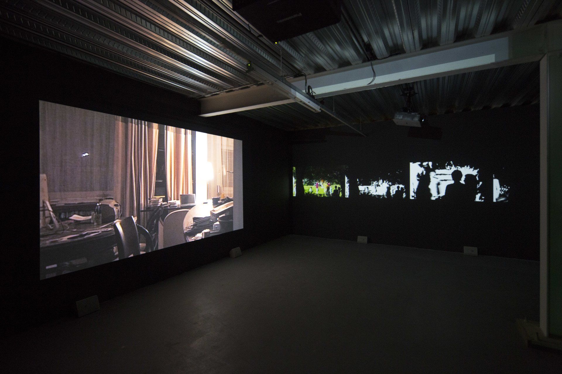 Um quarto escuro com muitas telas na parede.