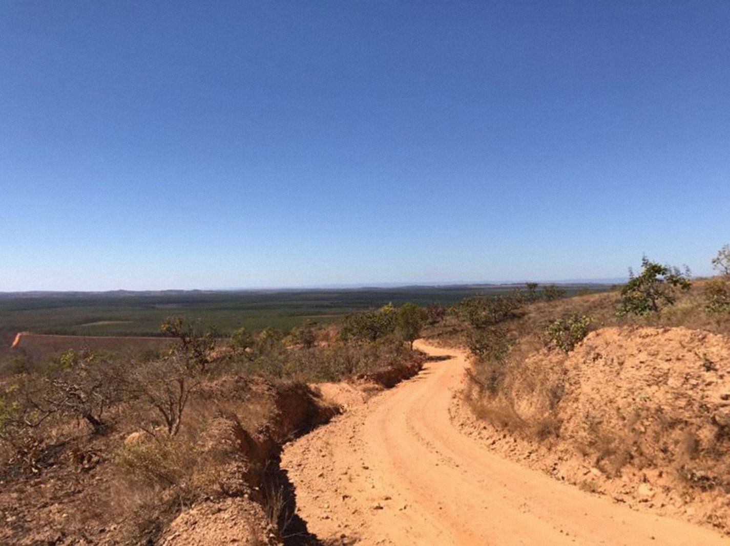 Uma estrada de terra passando por uma paisagem desértica com um céu azul ao fundo.