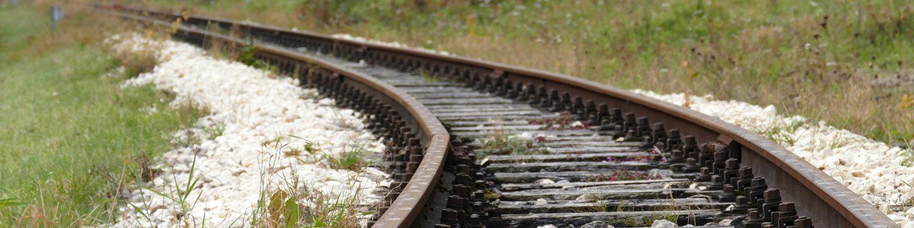 Um trilho de trem passa por um campo gramado.
