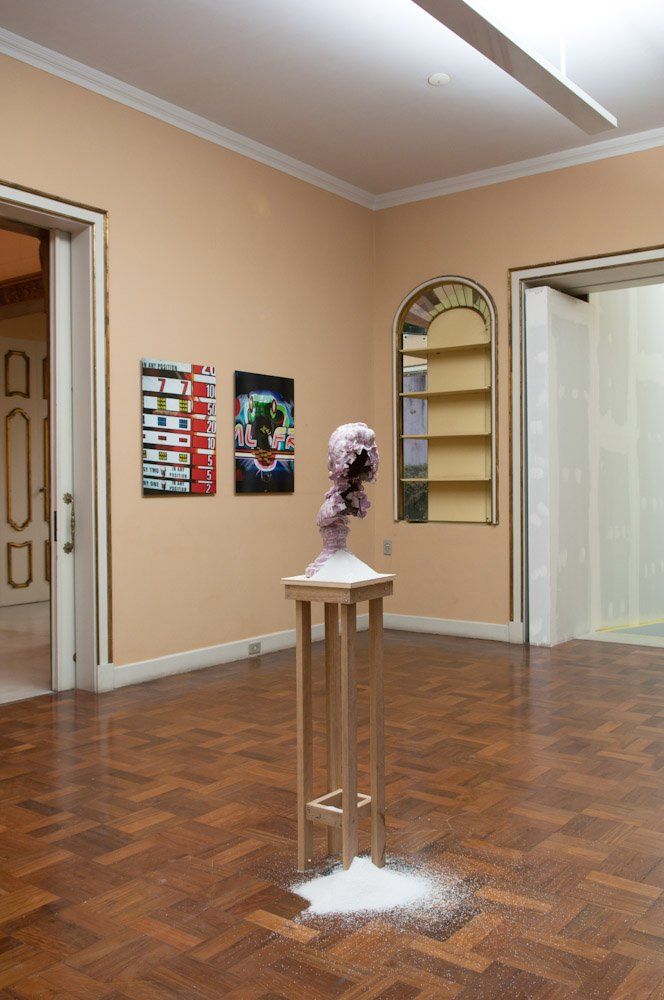 Uma sala com piso de madeira e uma estátua em um pedestal