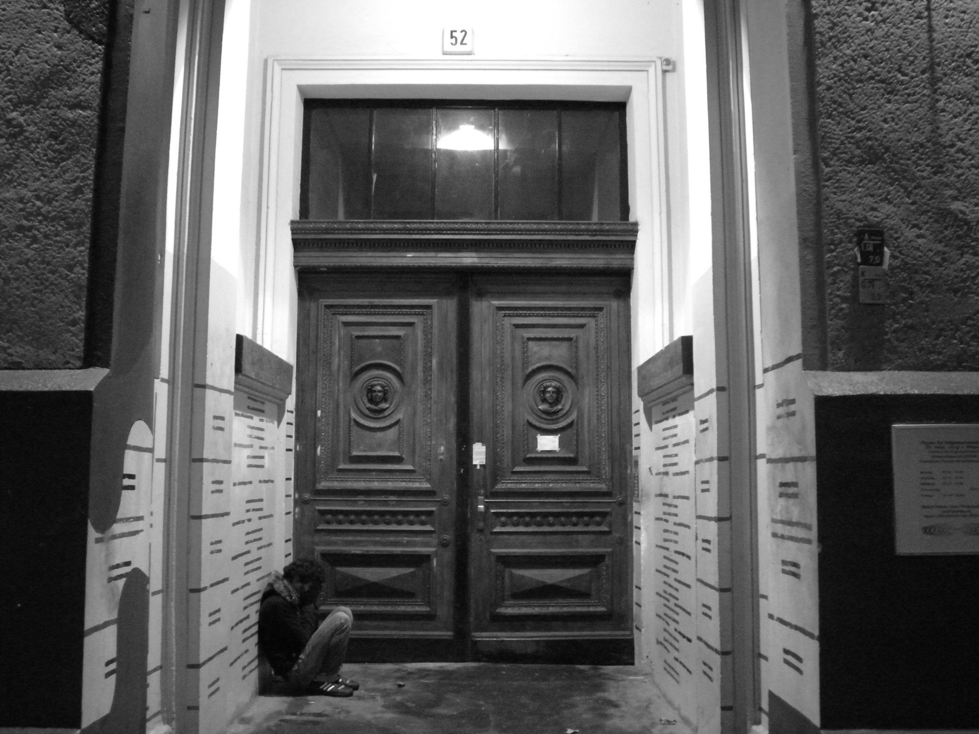 Uma foto em preto e branco de uma pessoa sentada em frente a uma porta