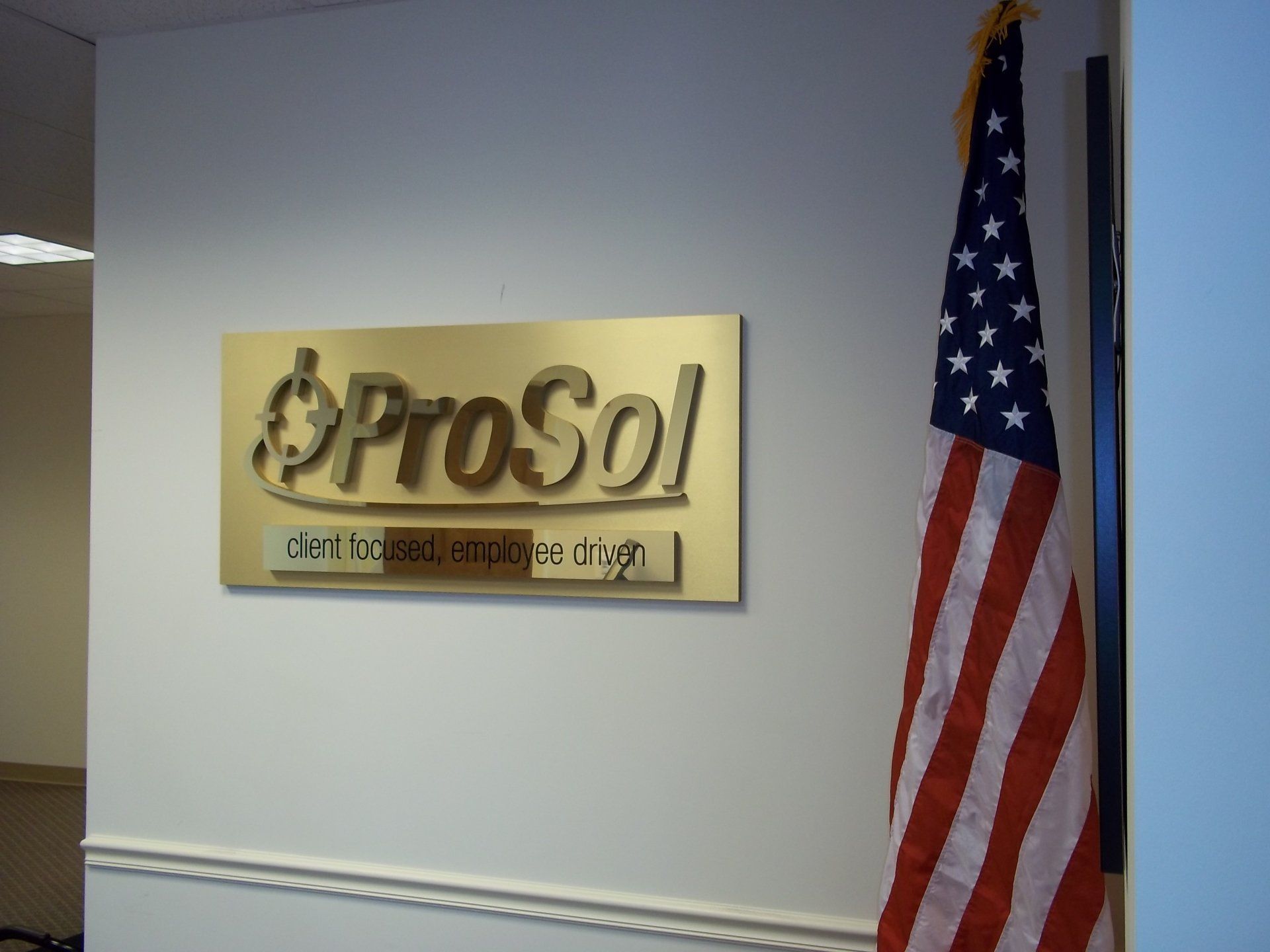 A prosol sign hangs on a wall next to an american flag