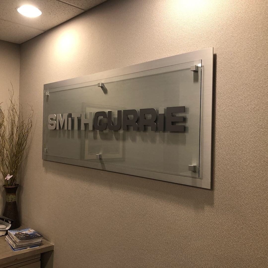 A sign that says smith currie is hanging on a wall.