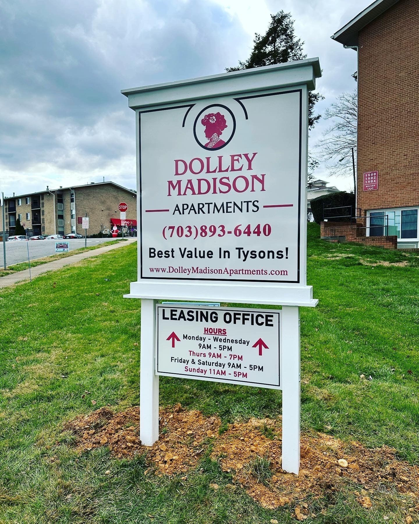 A sign for dolly madison apartments is in front of a brick building.