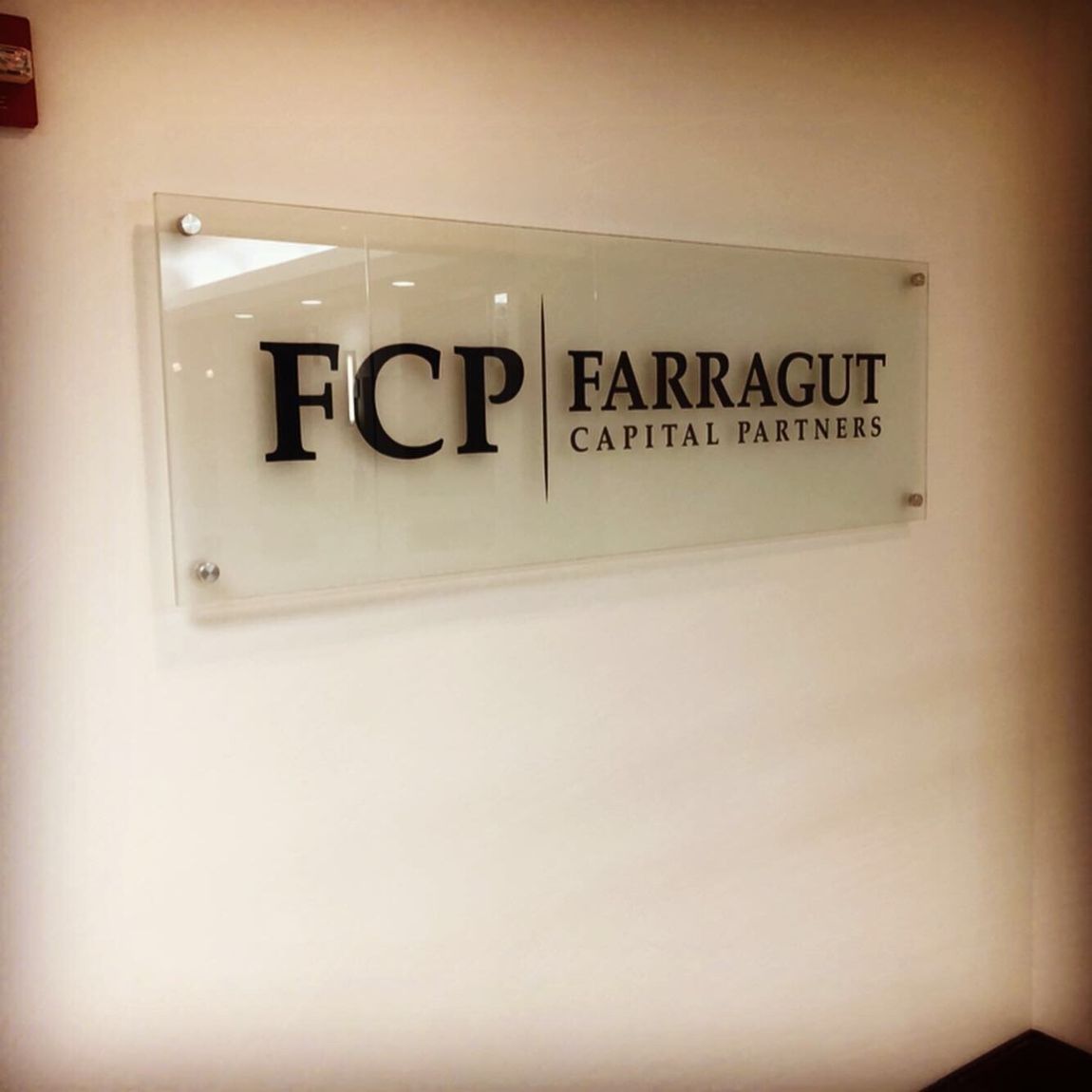 A glass sign that says fcp farragut capital partners