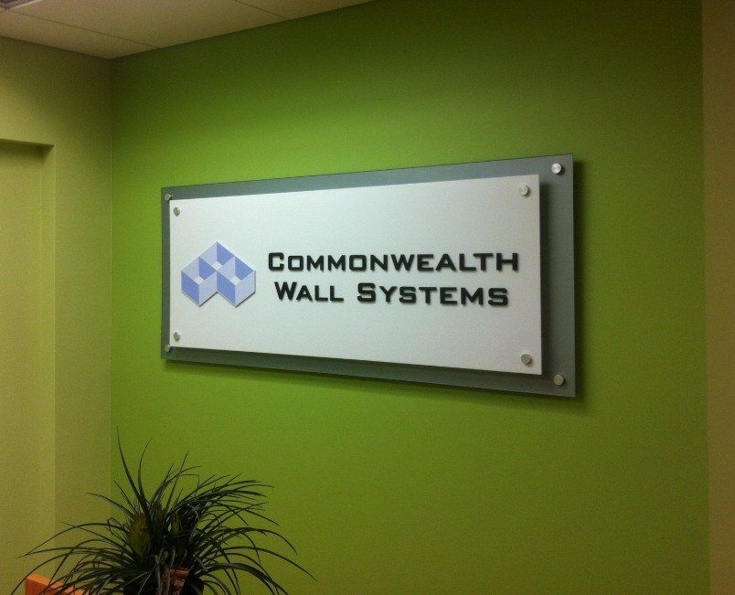 A sign for commonwealth wall systems hangs on a green wall