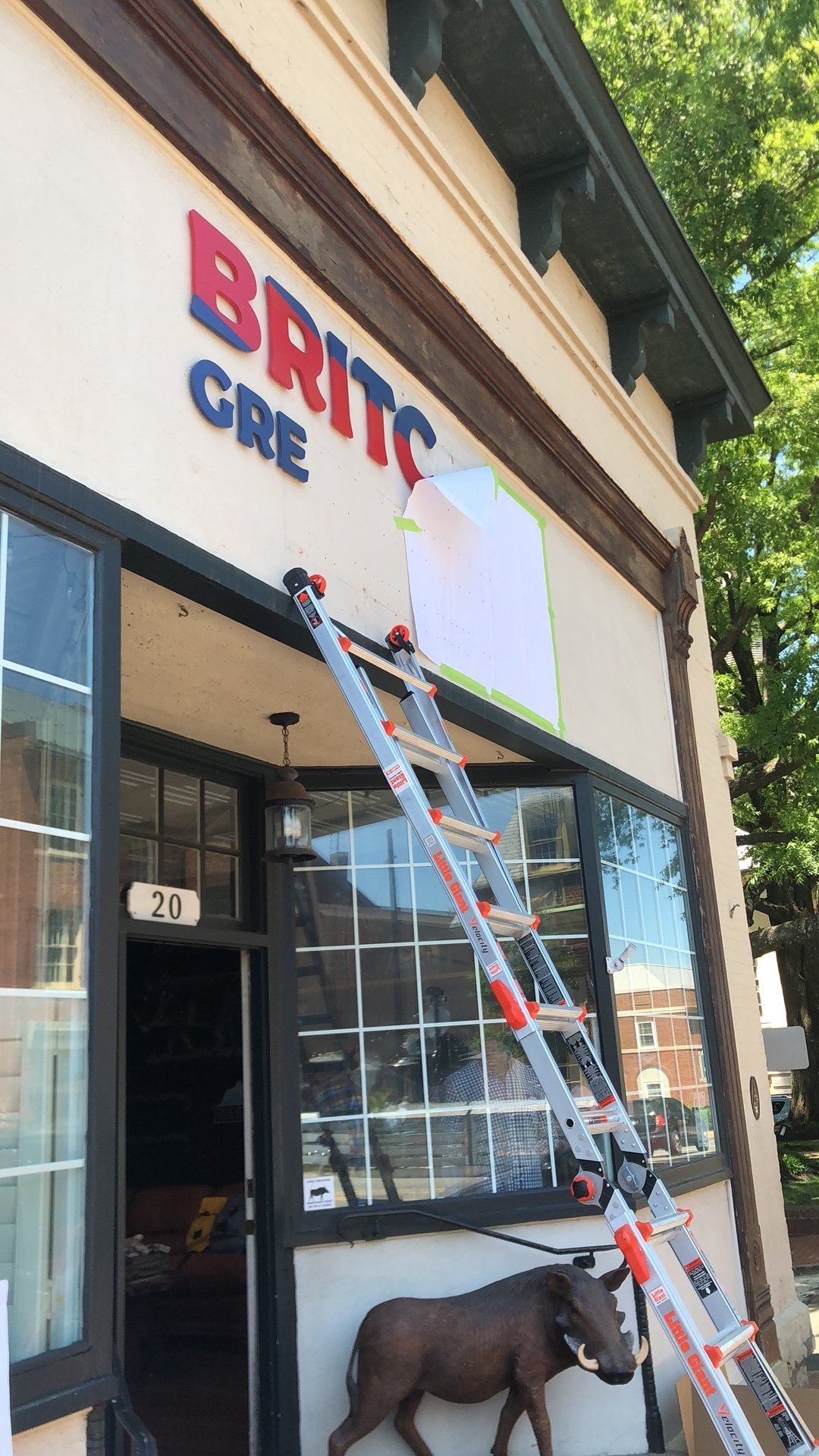 A ladder is hanging from the side of a building that says britc cre