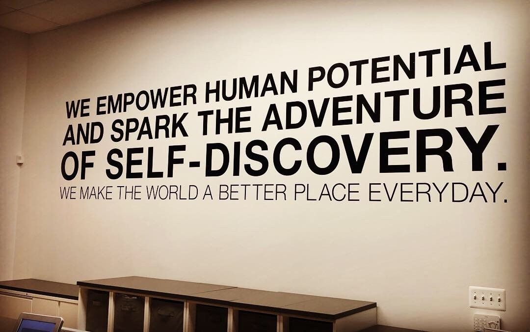 A wall with a quote that says we empower human potential and spark the adventure of self-discovery