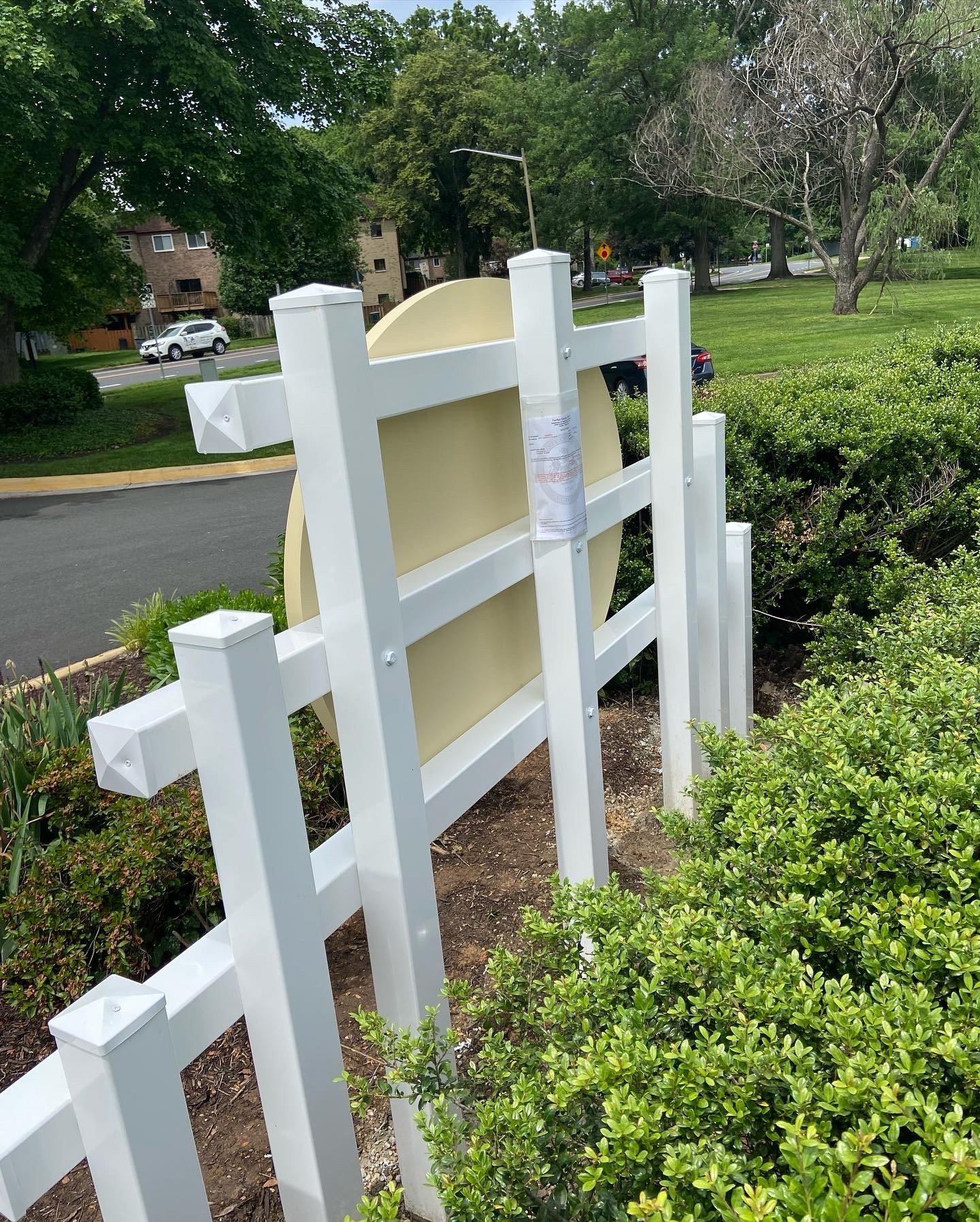 A white fence with a yellow sign behind it