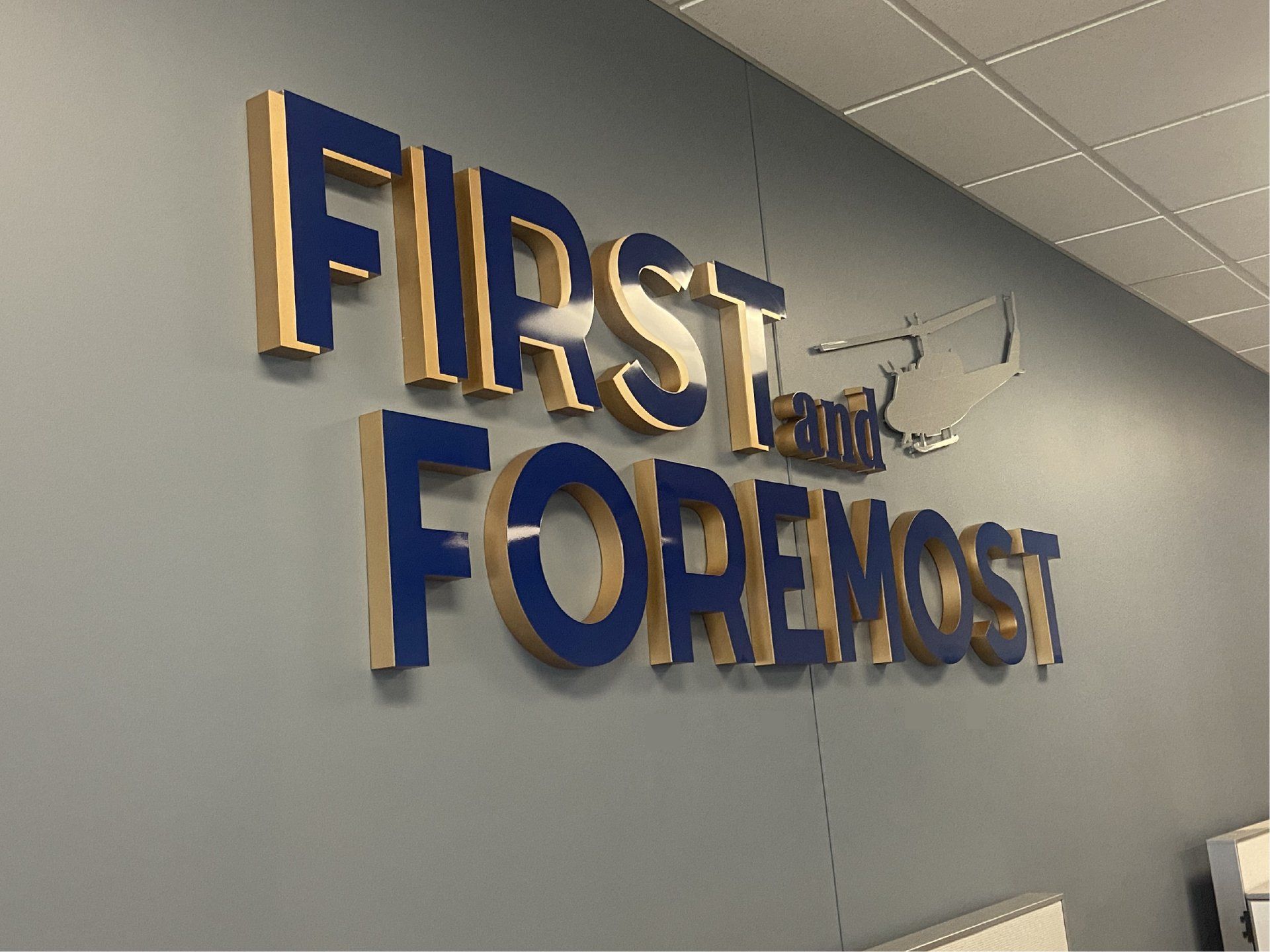 A blue and gold sign on a wall that says first foremost