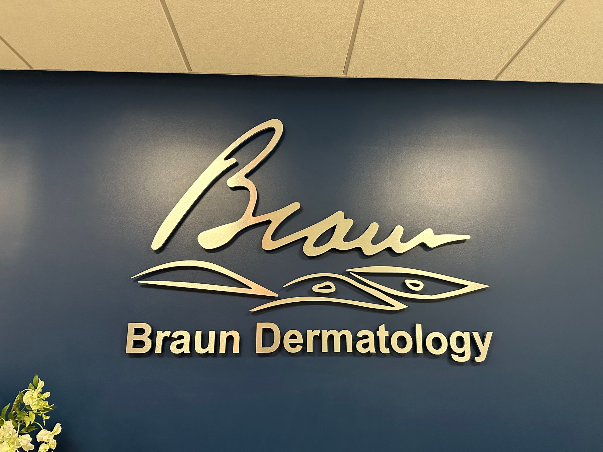 A sign for braun dermatology is on a blue wall