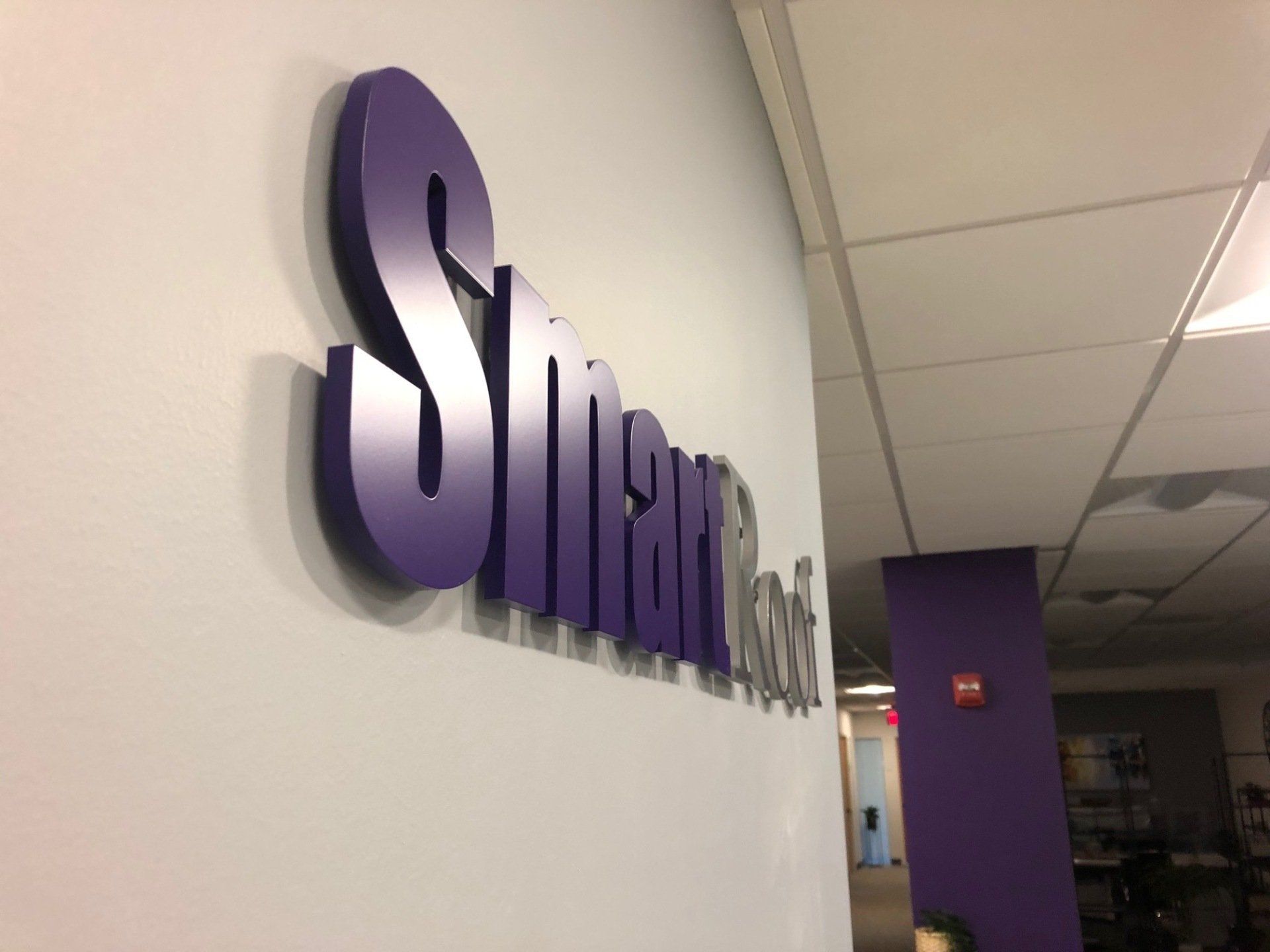 A purple sign that says smart on a white wall