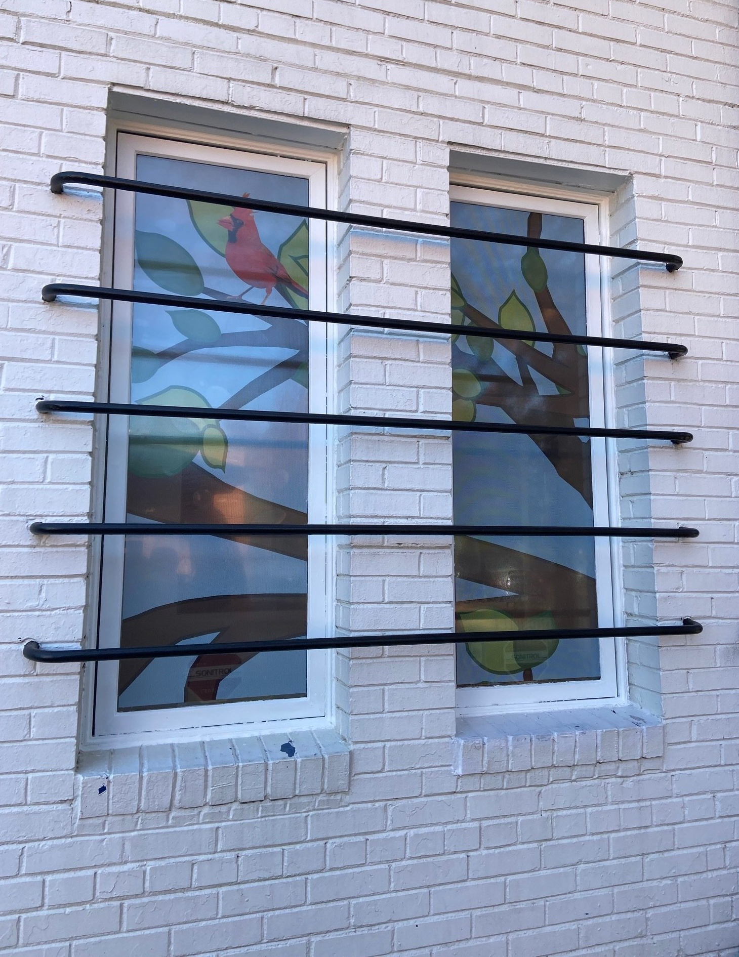 A white brick building with a window with a bird on it