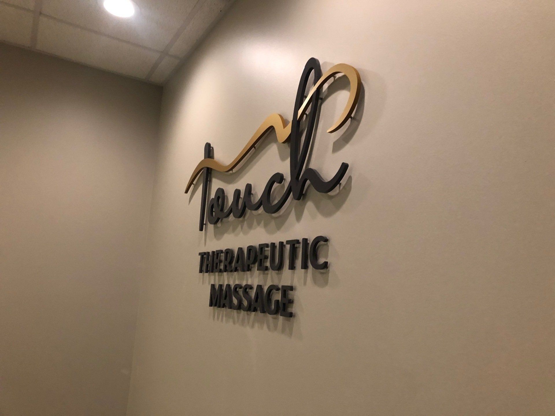 A sign on a wall that says touch therapeutic massage