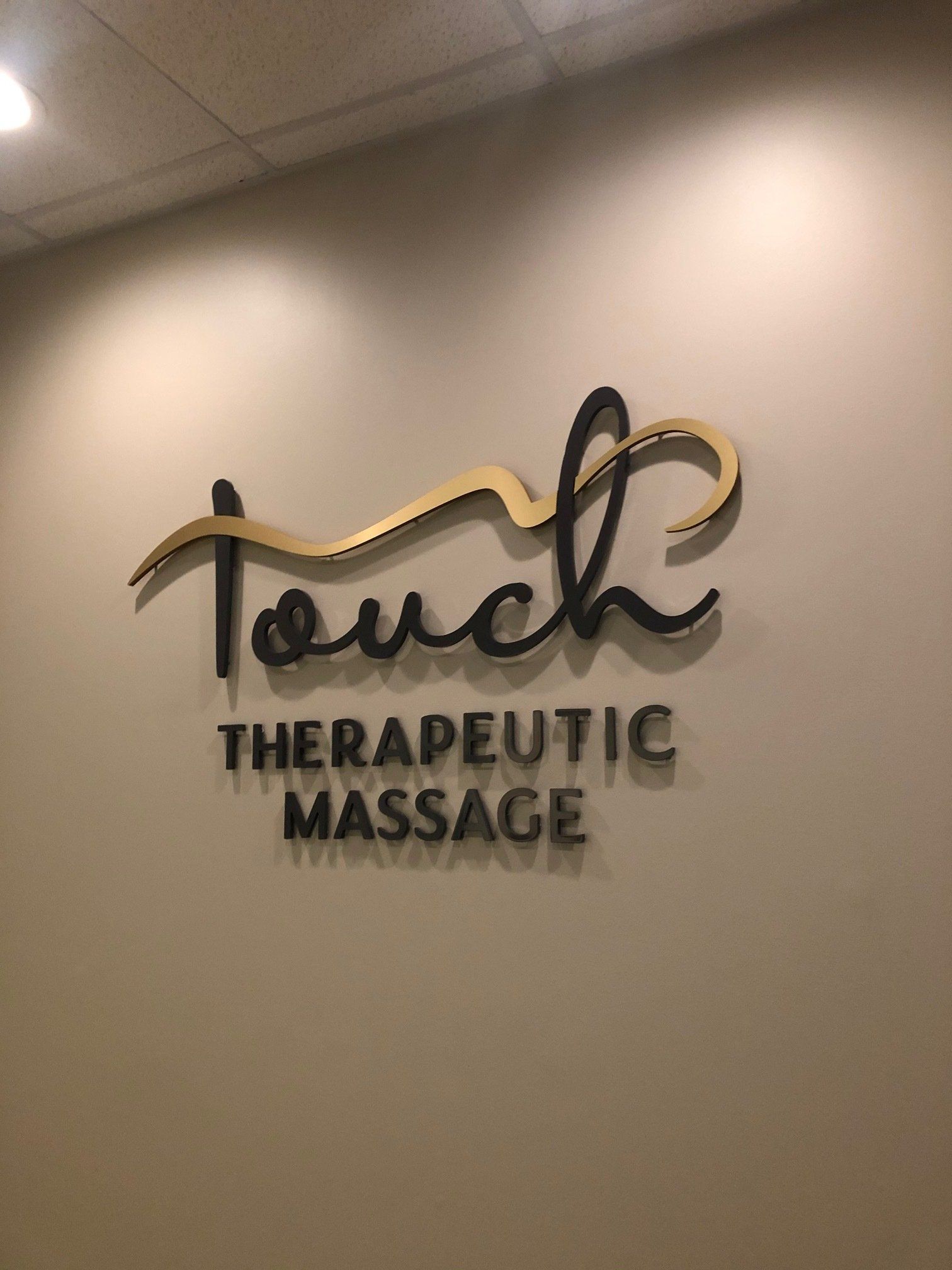 A sign on a wall that says touch therapeutic massage.