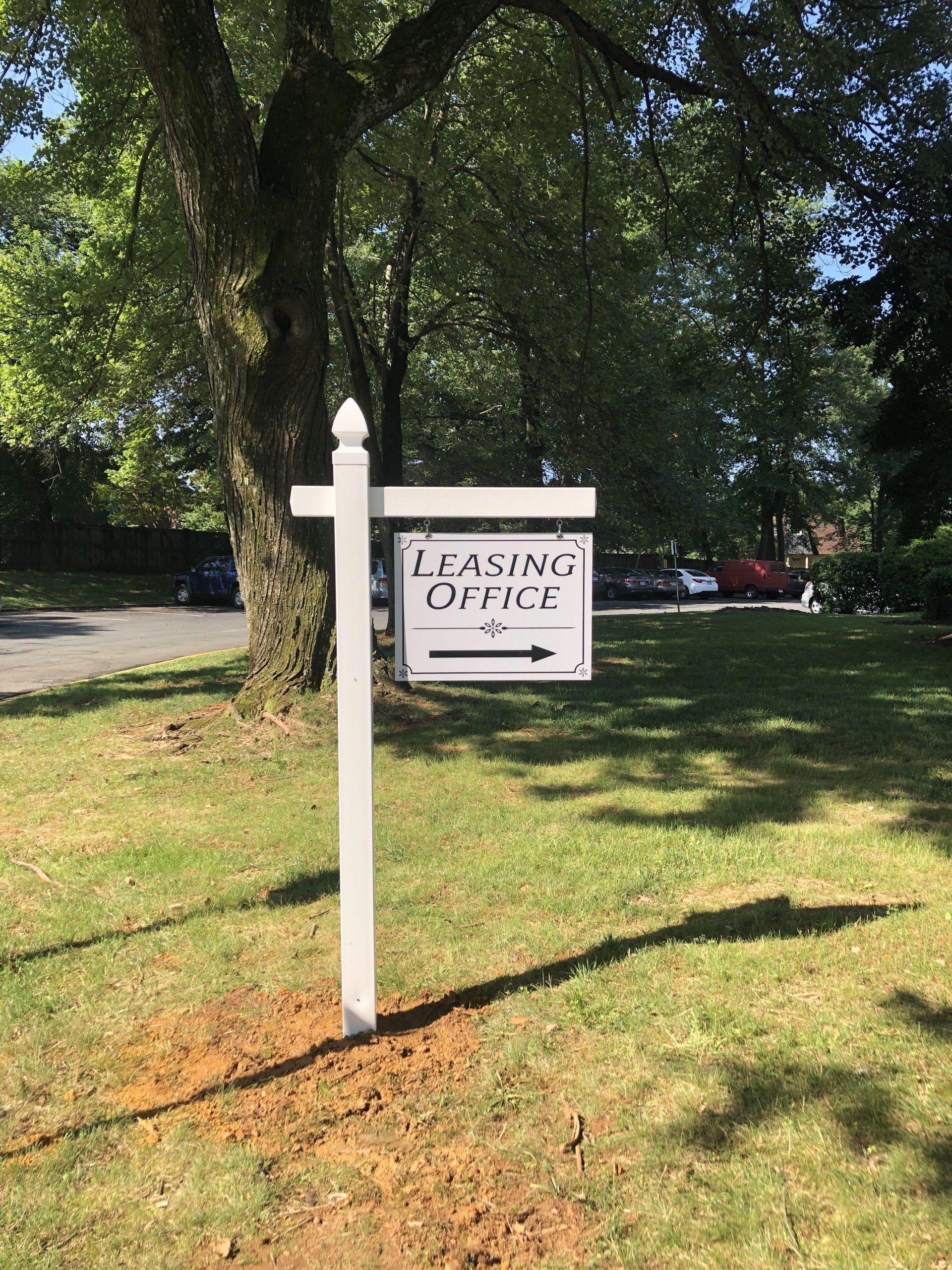 A white sign is sitting in the middle of a grassy field.