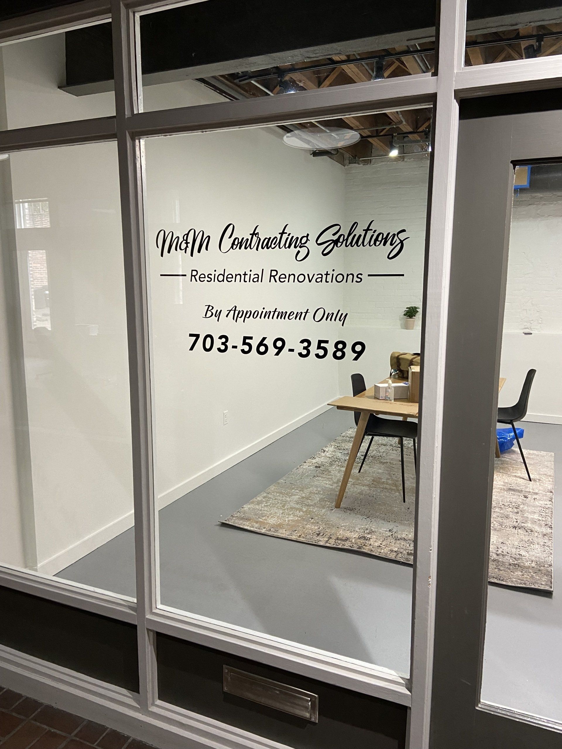 A room with a table and chairs in it is behind a glass door.