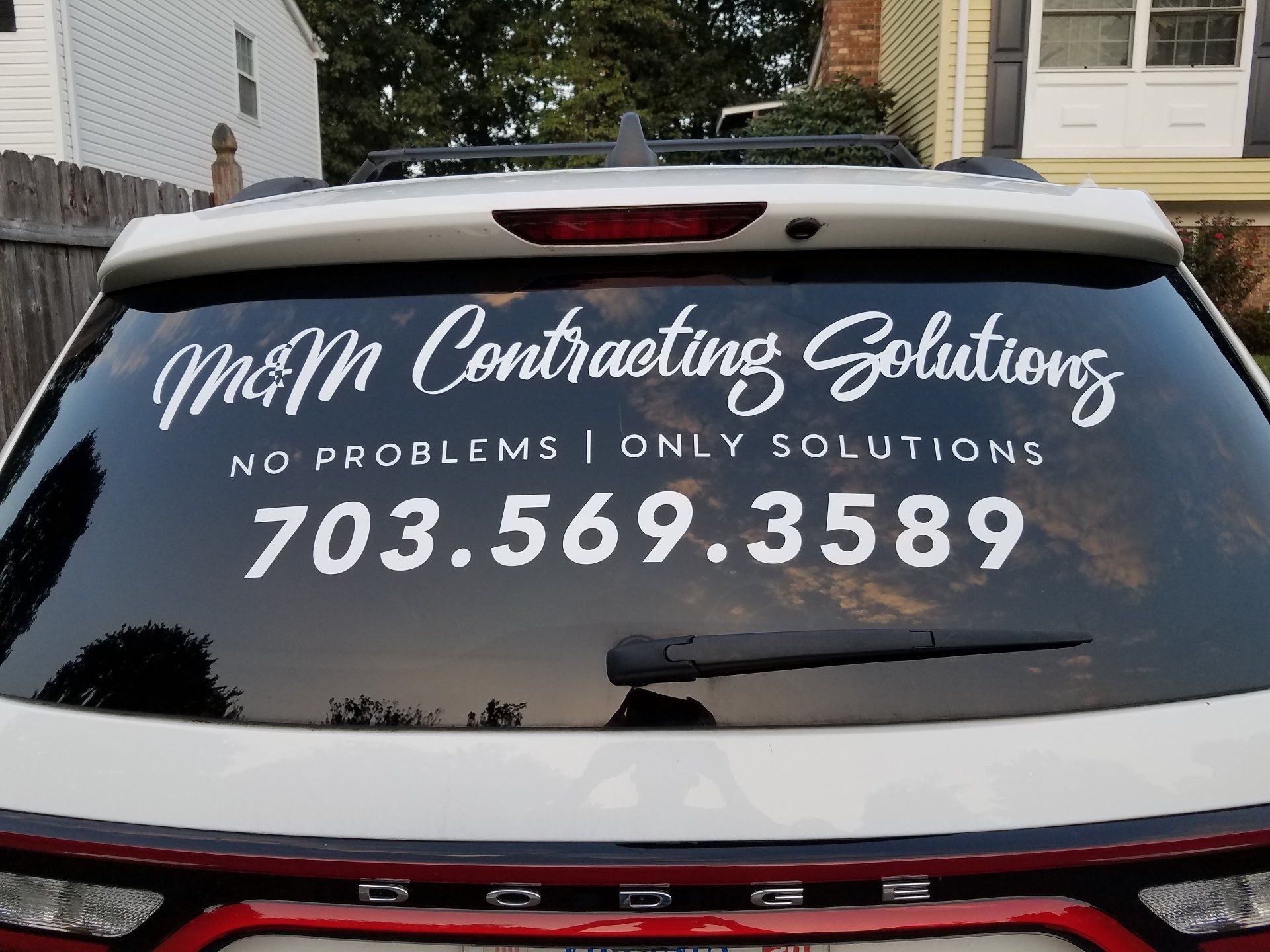 A car with a sticker on the back window that says mom contracting solutions