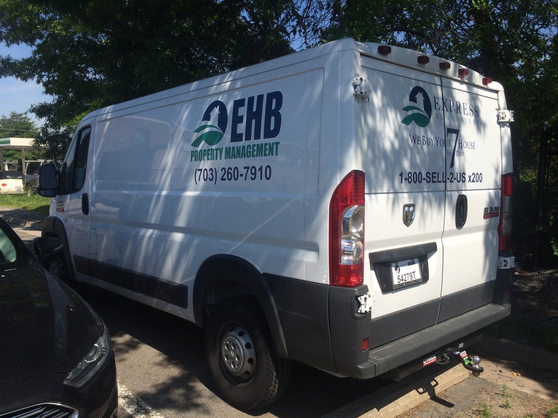 A white van is parked in a parking lot next to a black car.