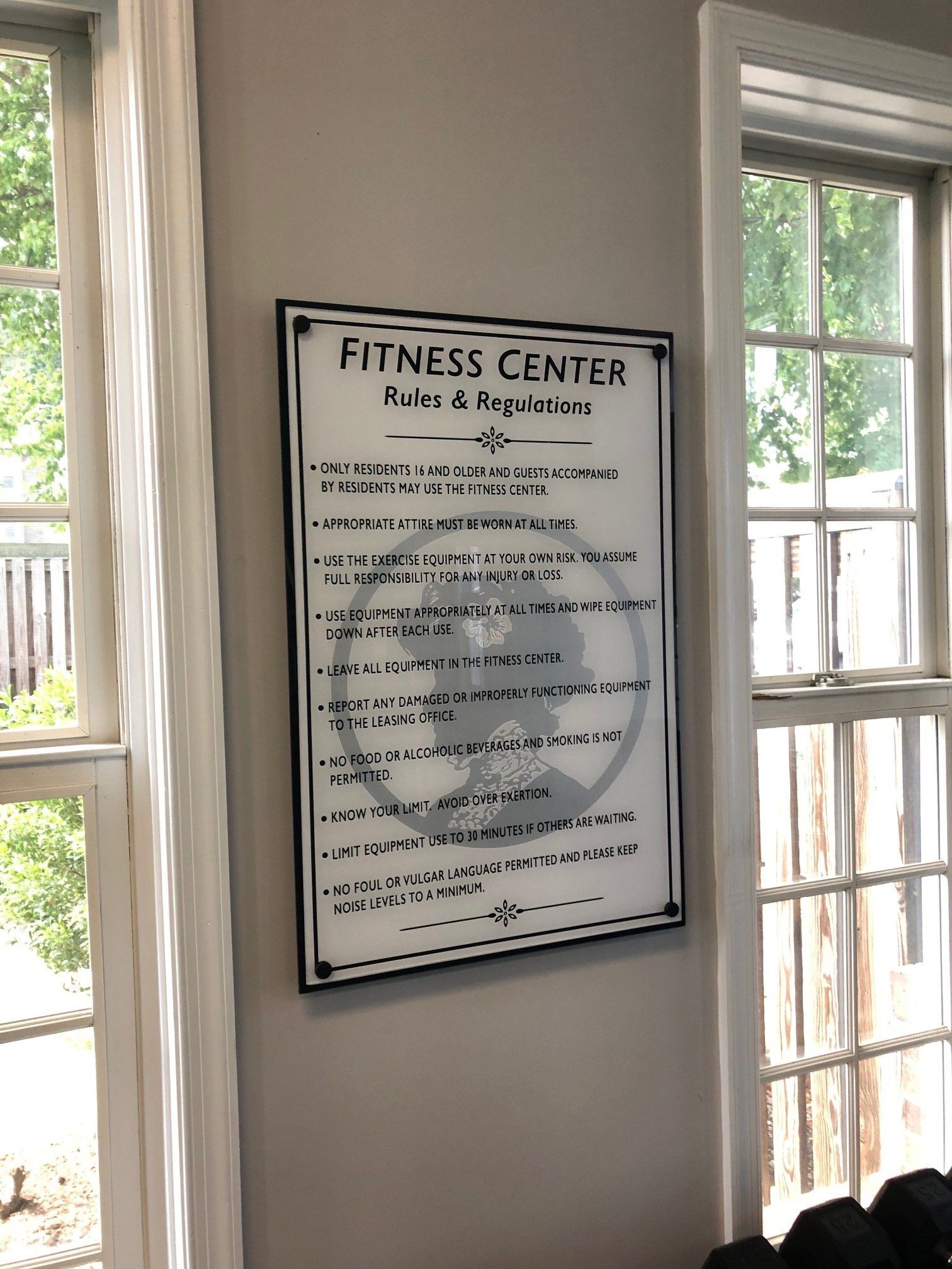 A sign for the fitness center is hanging on a wall next to a window.