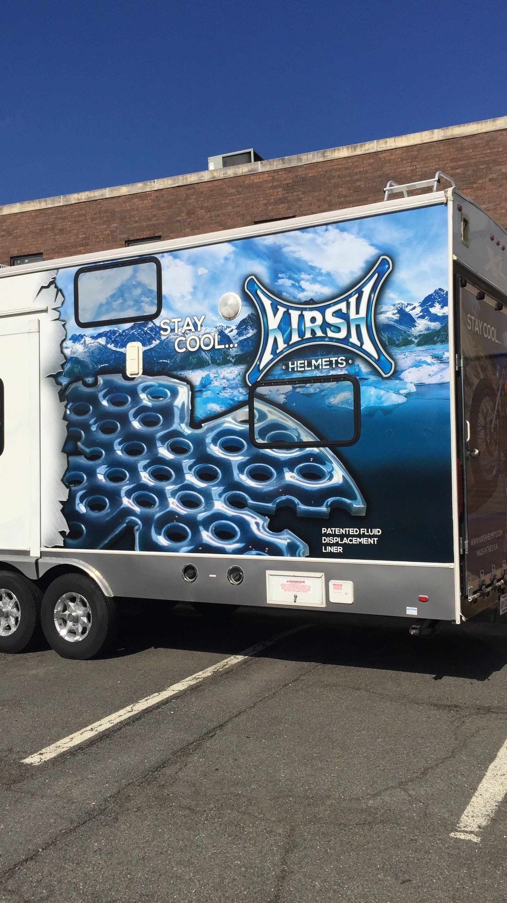 A trailer is parked in a parking lot in front of a building.