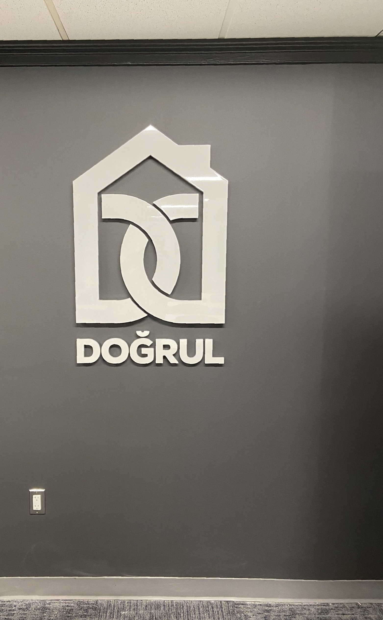 A dogrul logo is on a black wall.