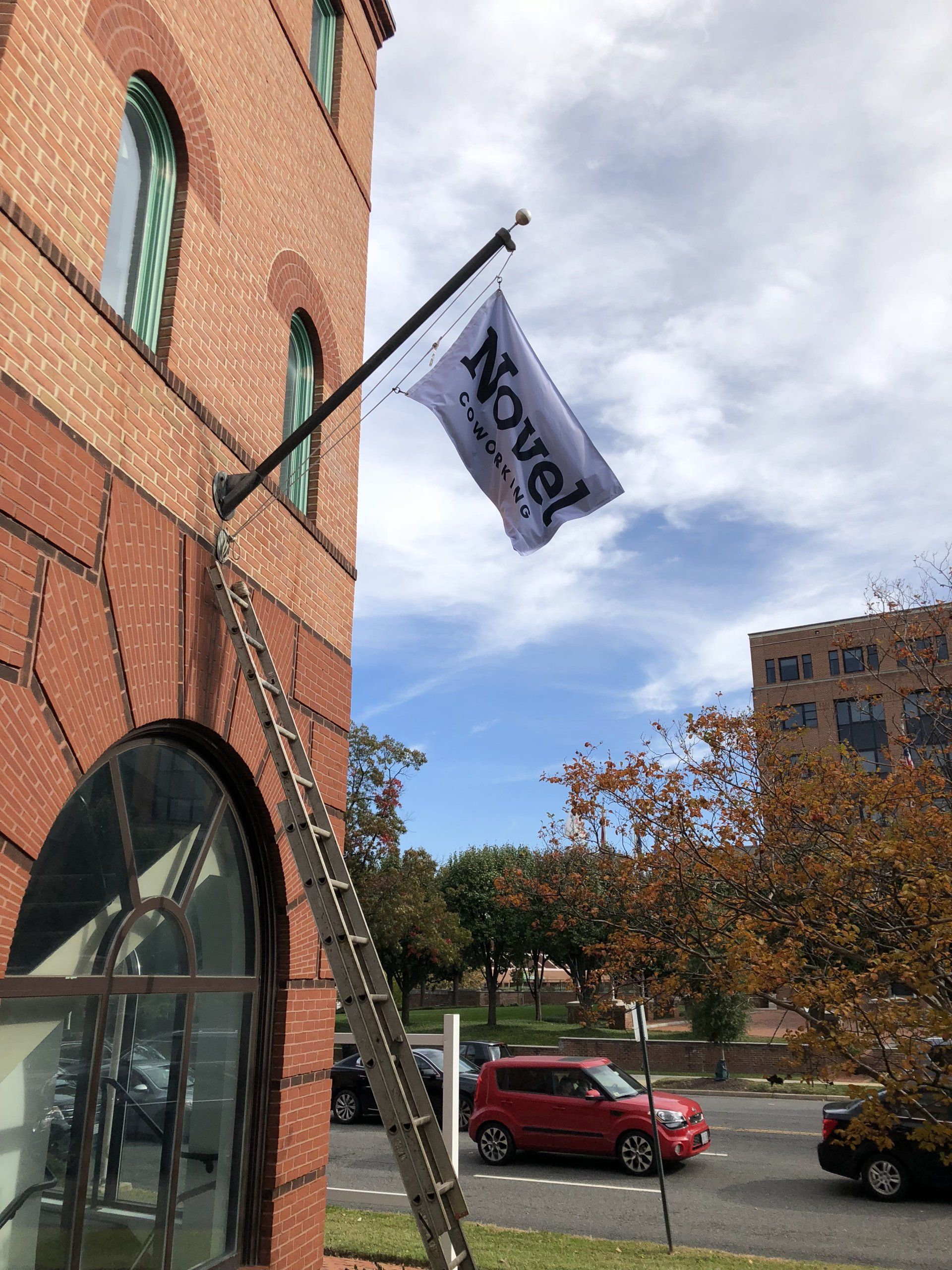 A novel flag is hanging from a pole on the side of a building.