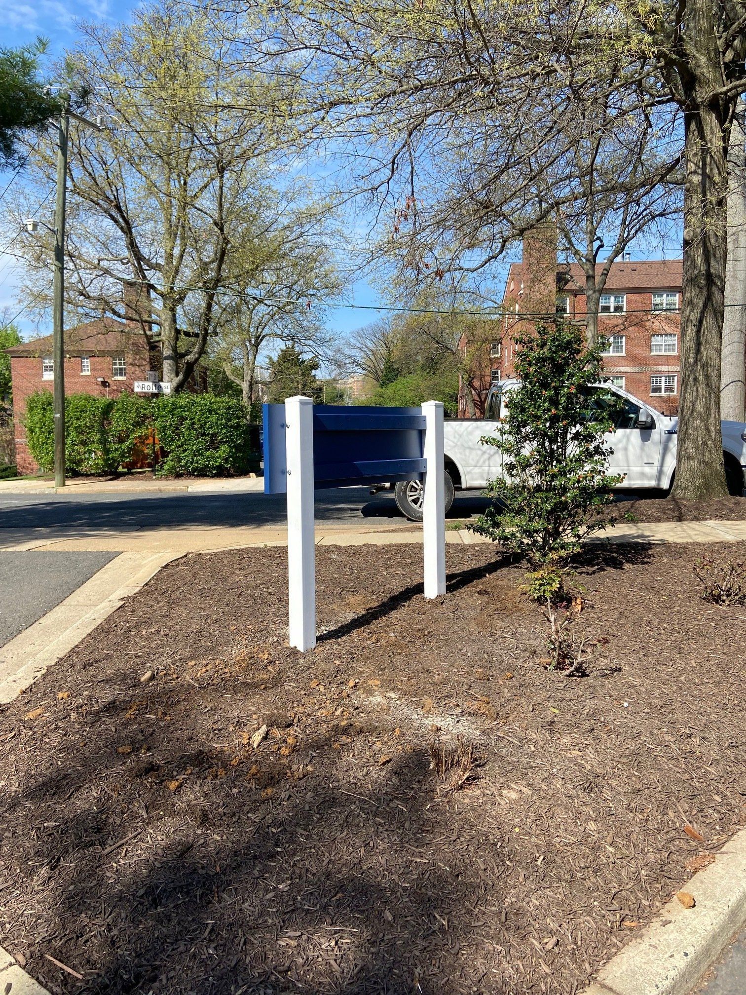 A white truck is parked in a parking lot next to a tree.