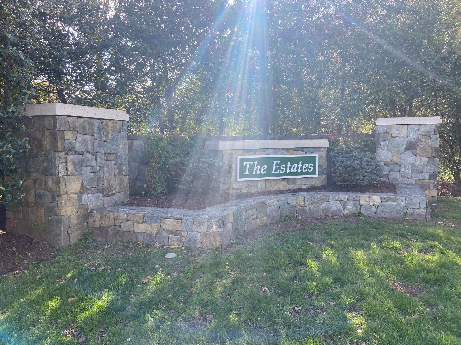 A stone wall with a sign that says the estates