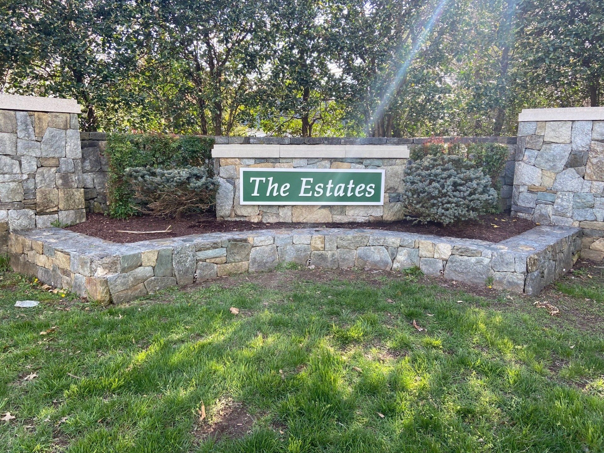 A stone wall with a sign that says `` the estates '' on it.
