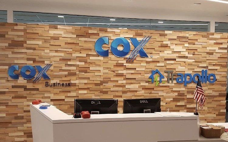 A reception area with a wooden wall and a sign that says cox business