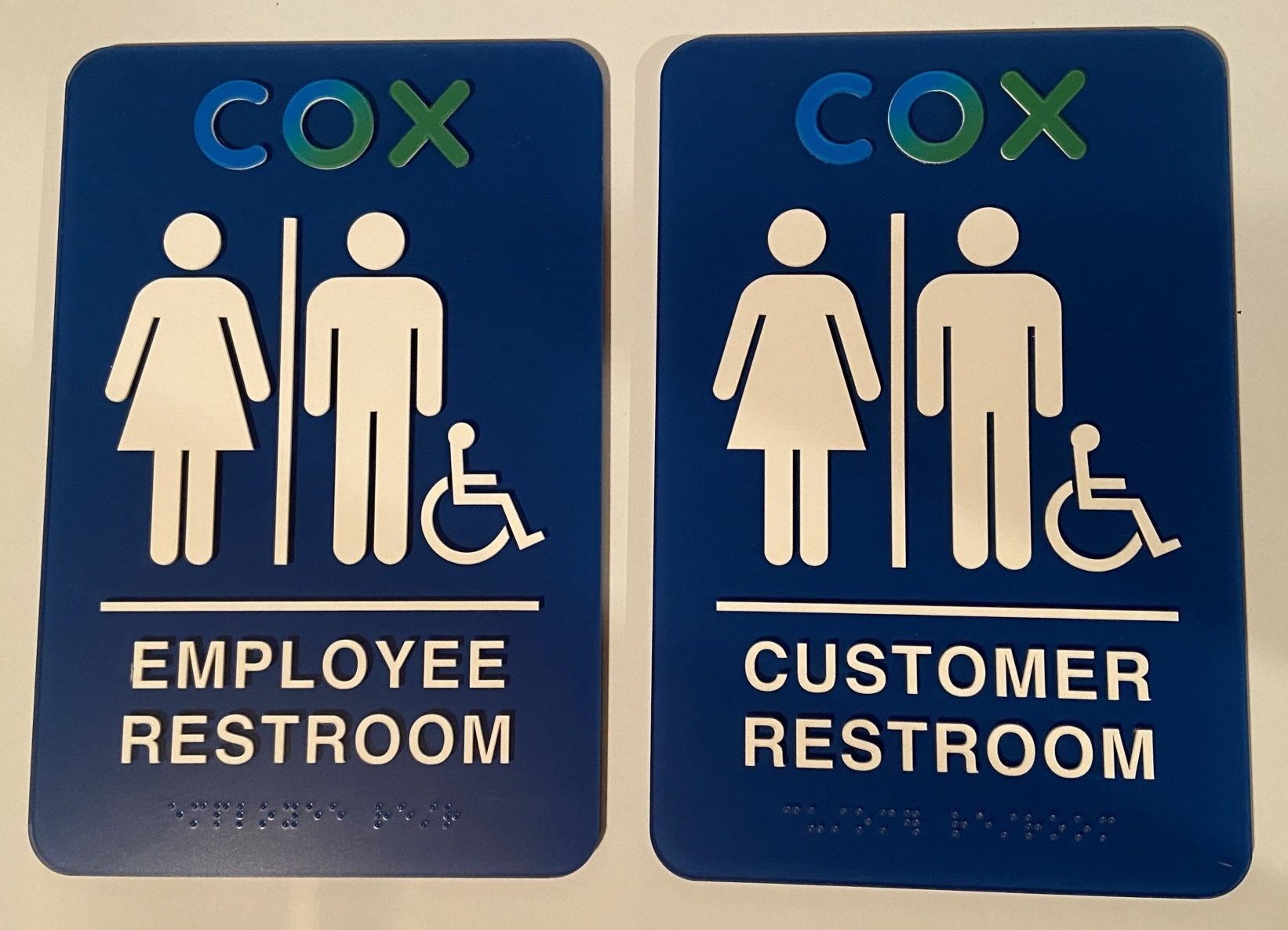 Two blue signs that say cox employee restroom and customer restroom