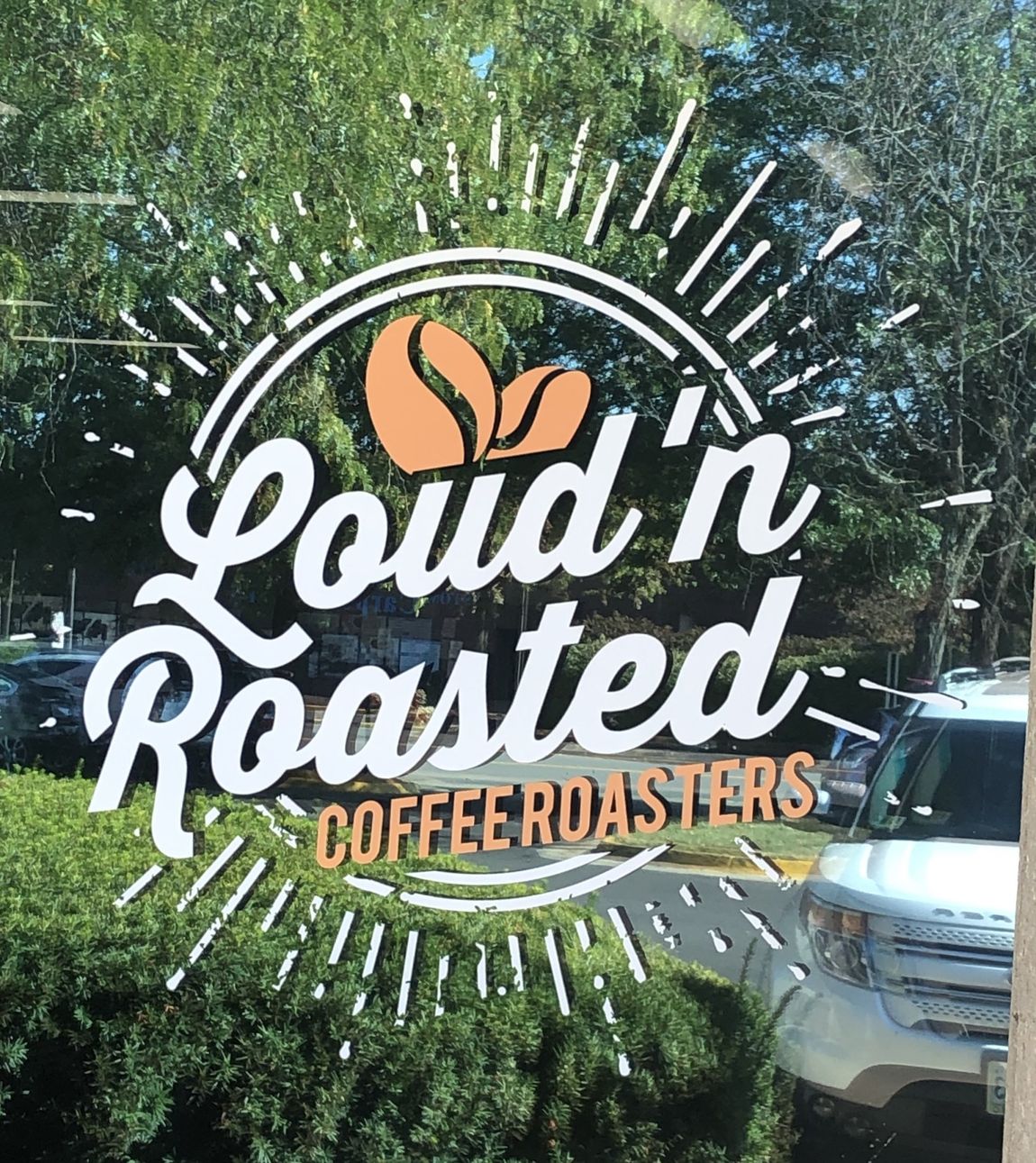 A sign for loud n roasted coffee roasters is on a window.