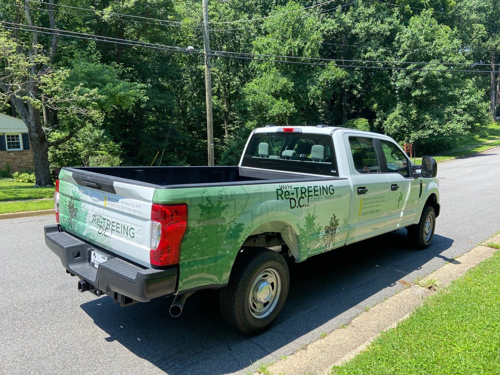 A green and white truck is parked on the side of the road.