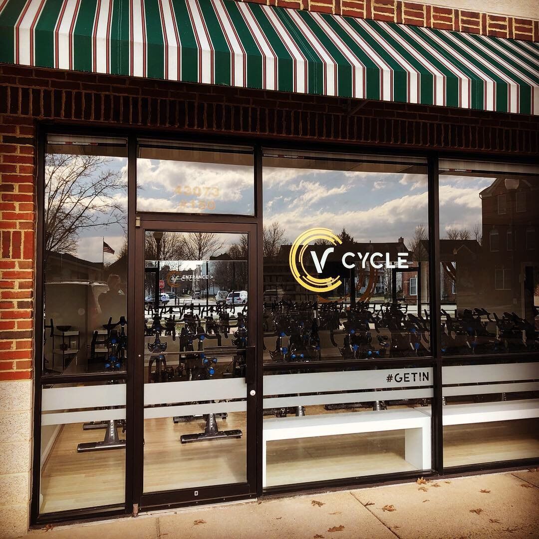 A gym with a green and white awning that says v cycle