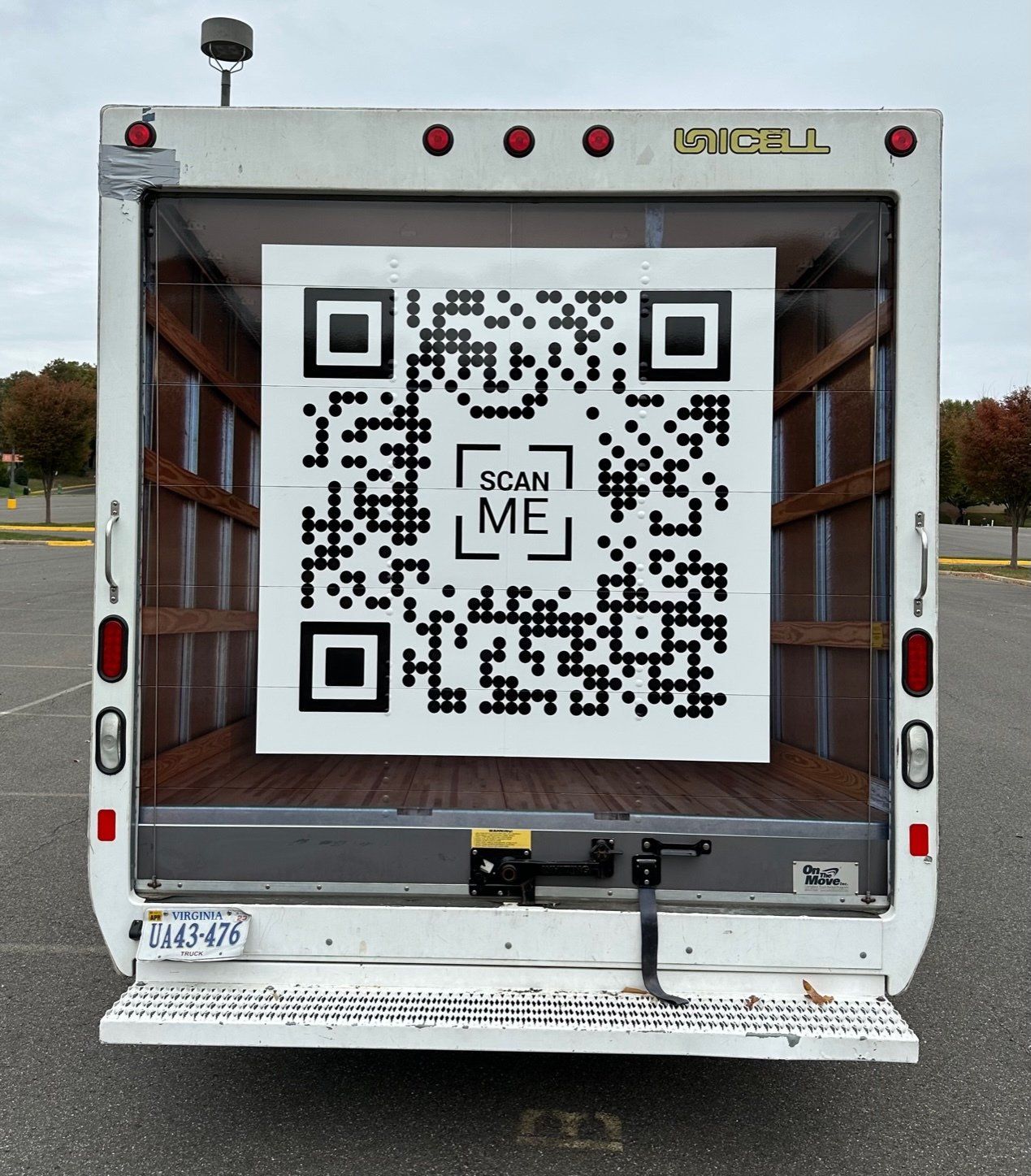 A white truck has a qr code on the back that says scan me
