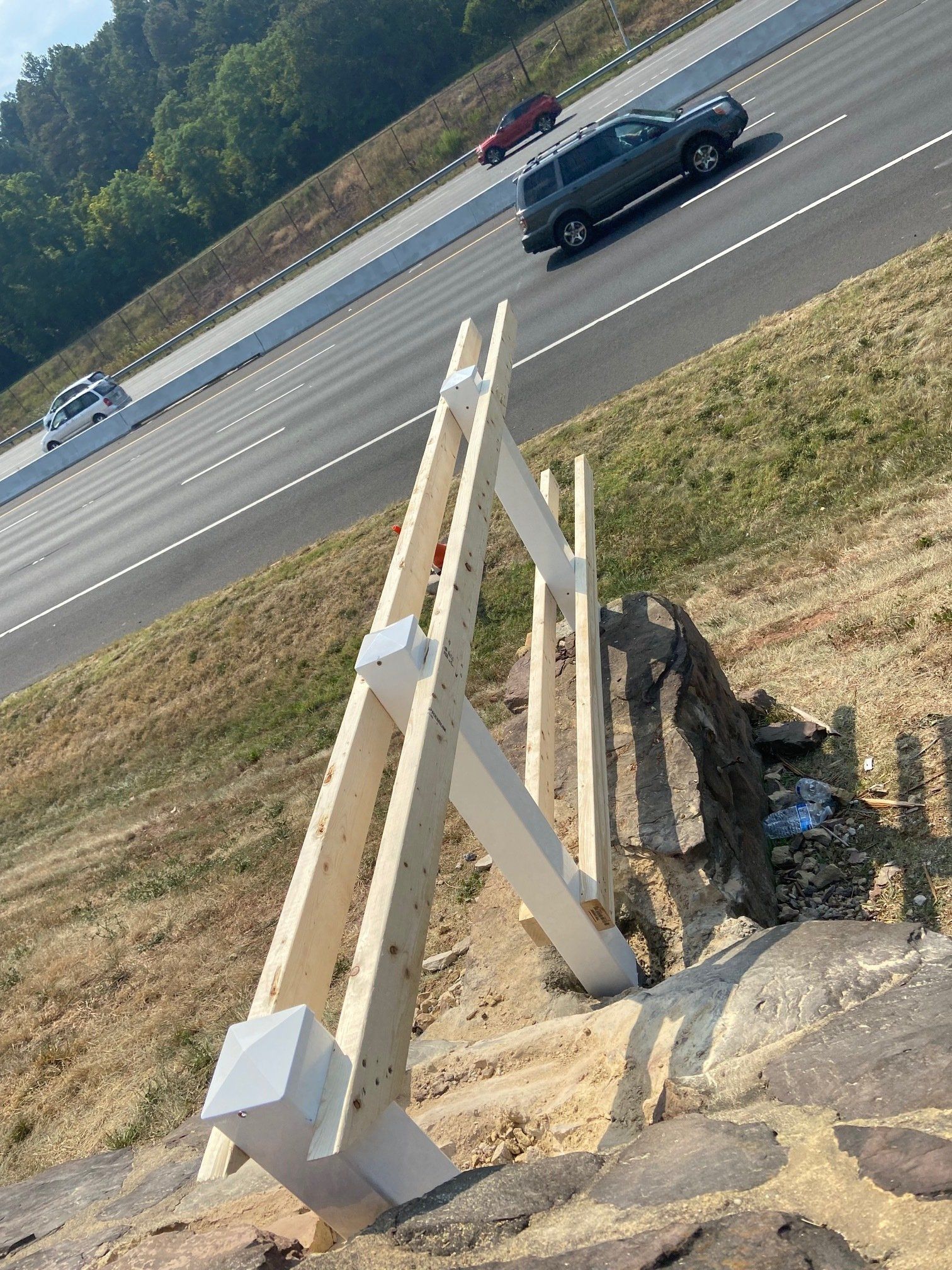 A car is driving down a highway next to a wooden fence.