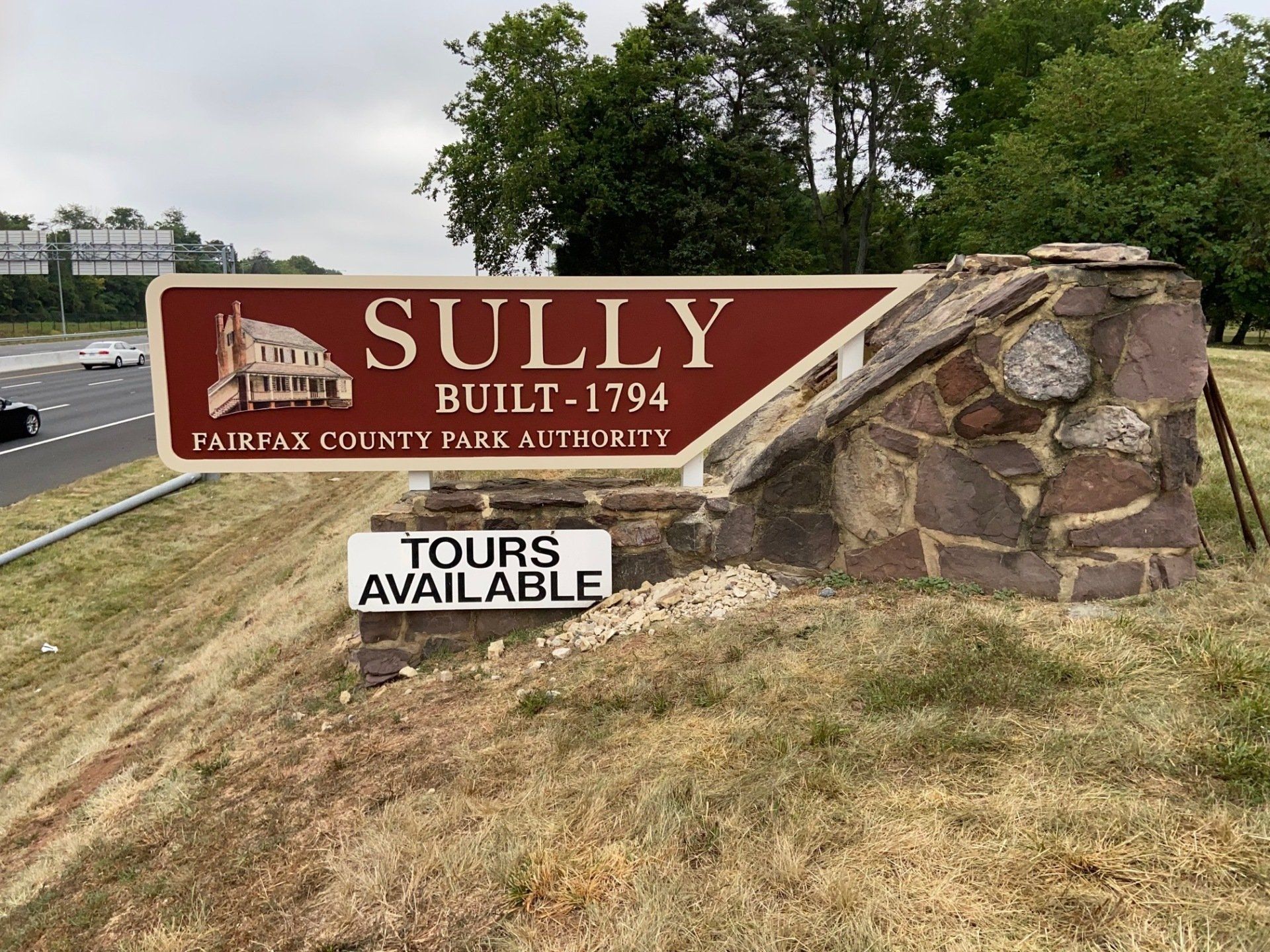A sign for sully built in 1794 is sitting on top of a stone wall.