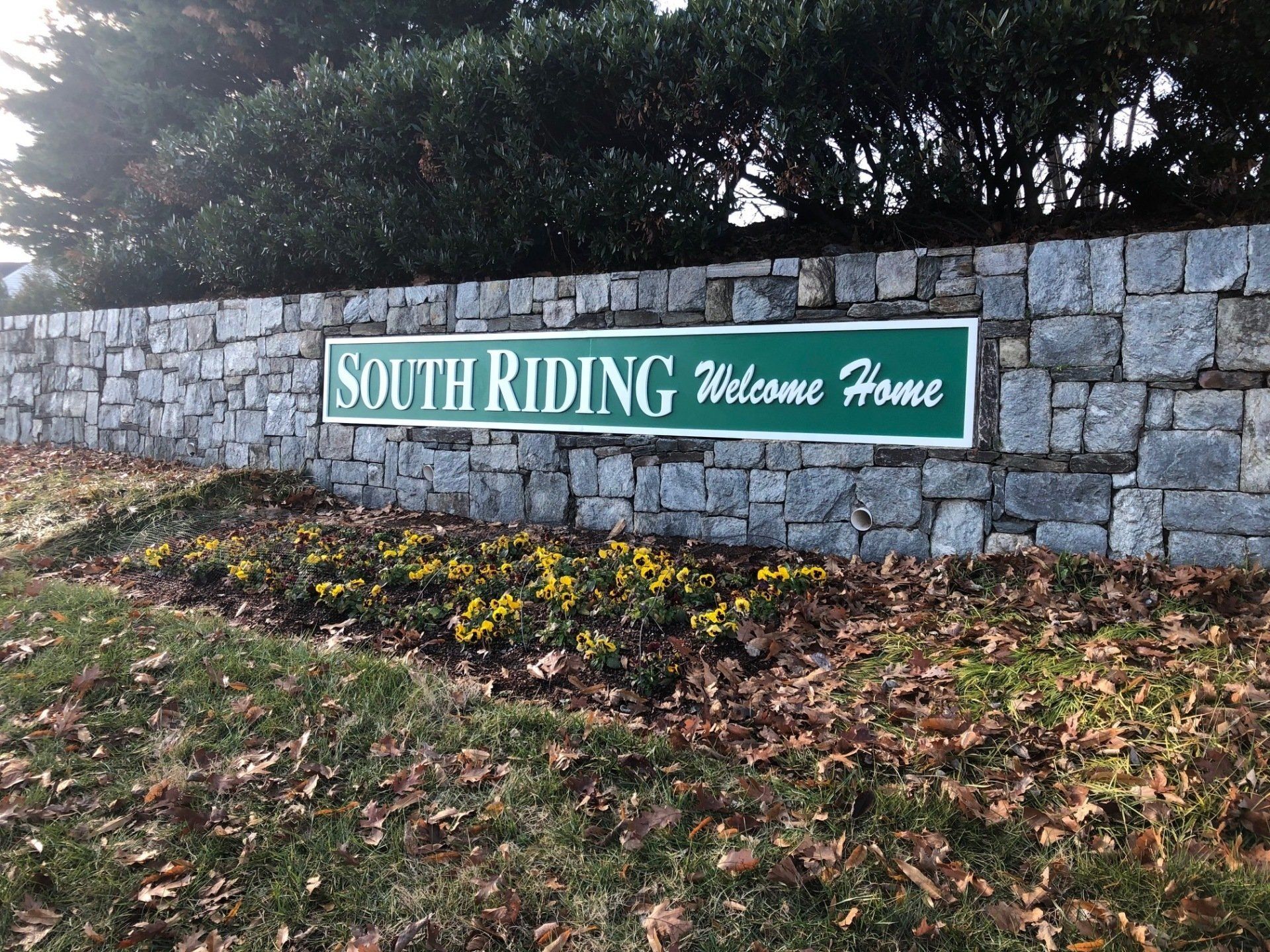 A stone wall with a sign that says south riding welcome home