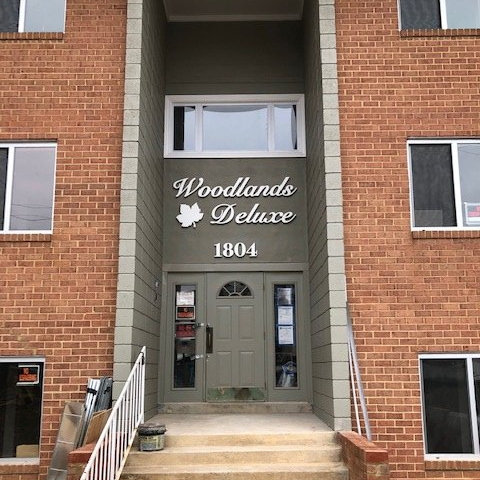 A brick building with a sign that says woodlands deluxe 1804