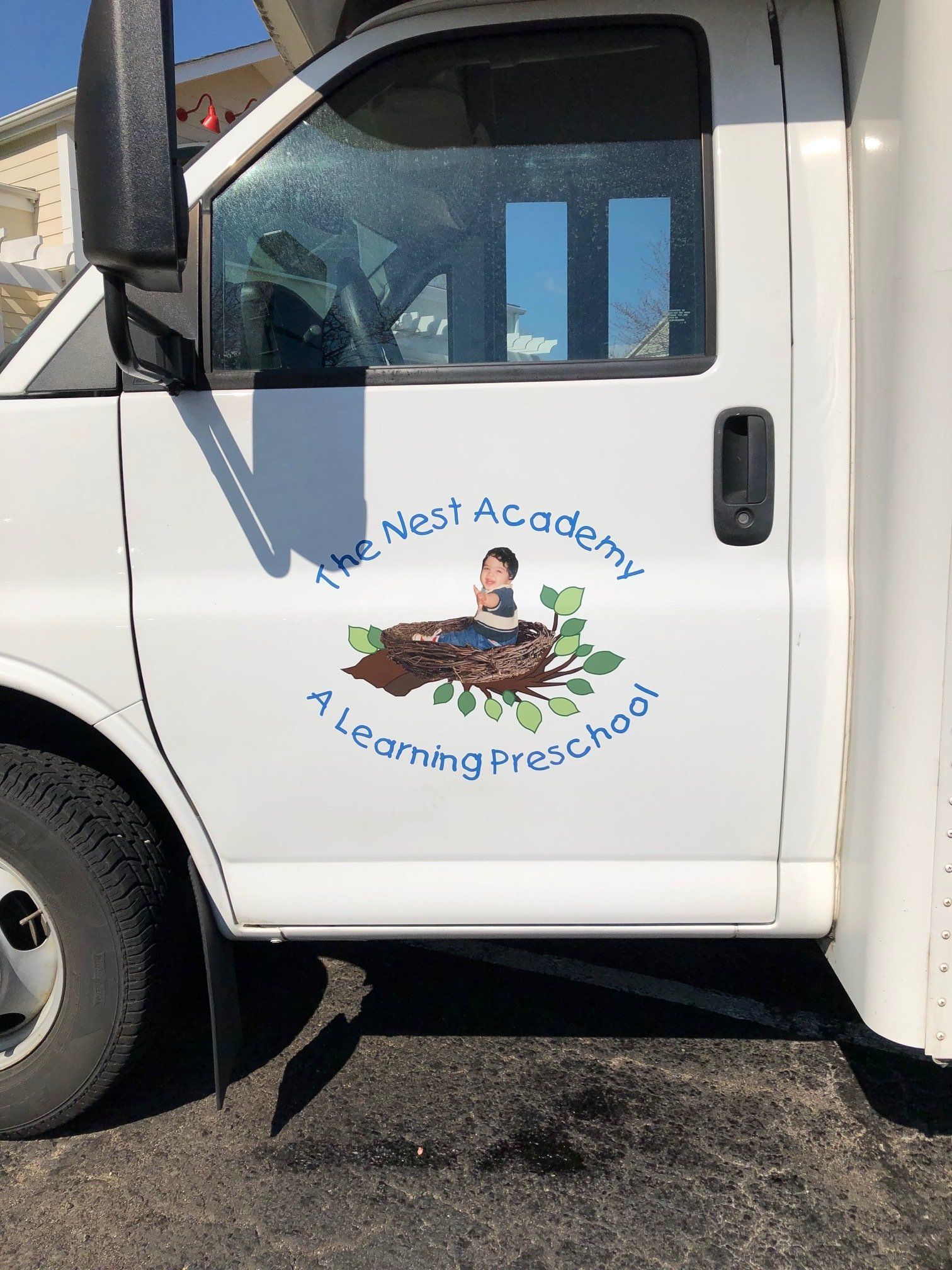 A white van with a sticker on the side that says the nest academy a learning preschool